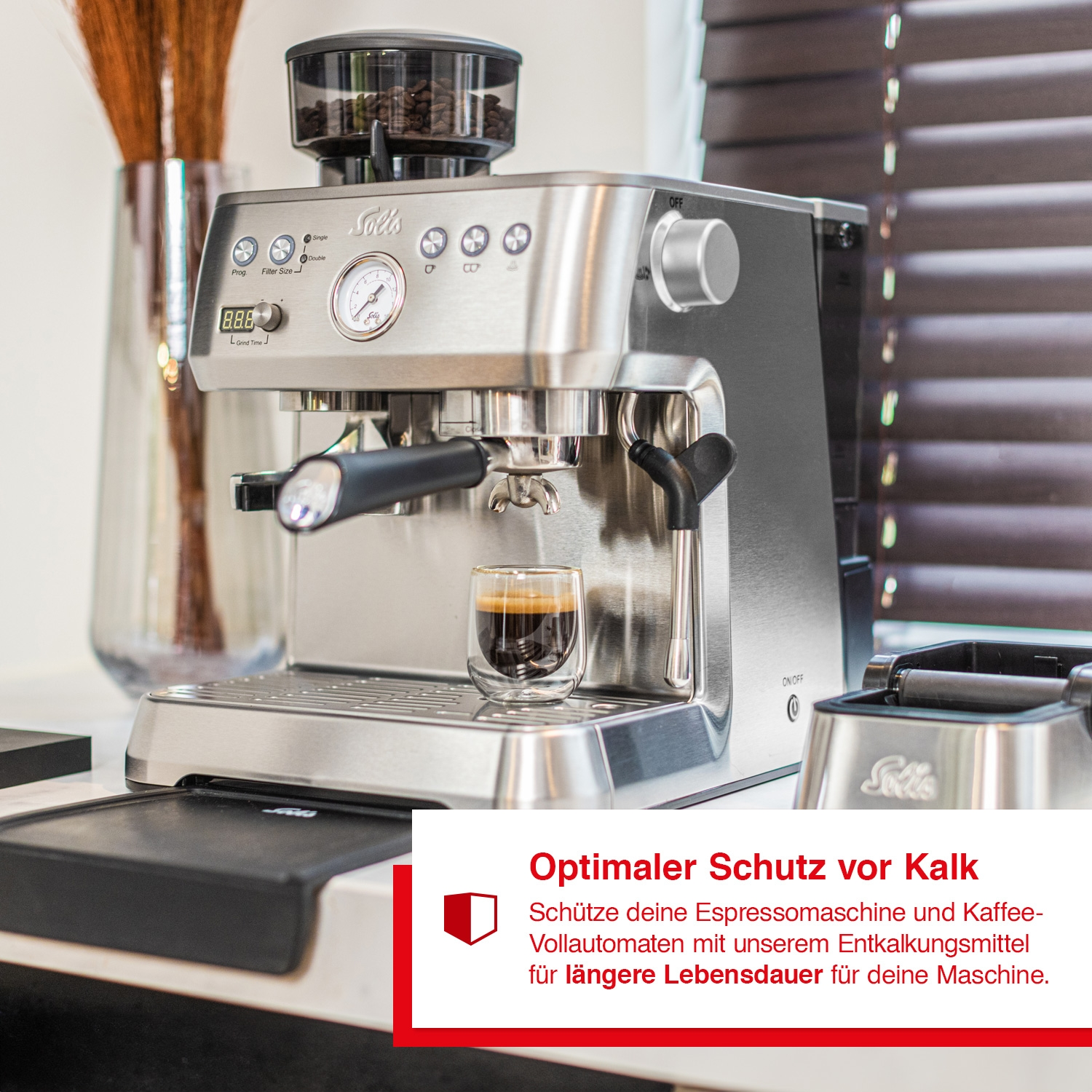 Eine silberne Espressomaschine mit einem Glas Kaffee und einem Textfeld, das den Schutz vor Kalk betont.