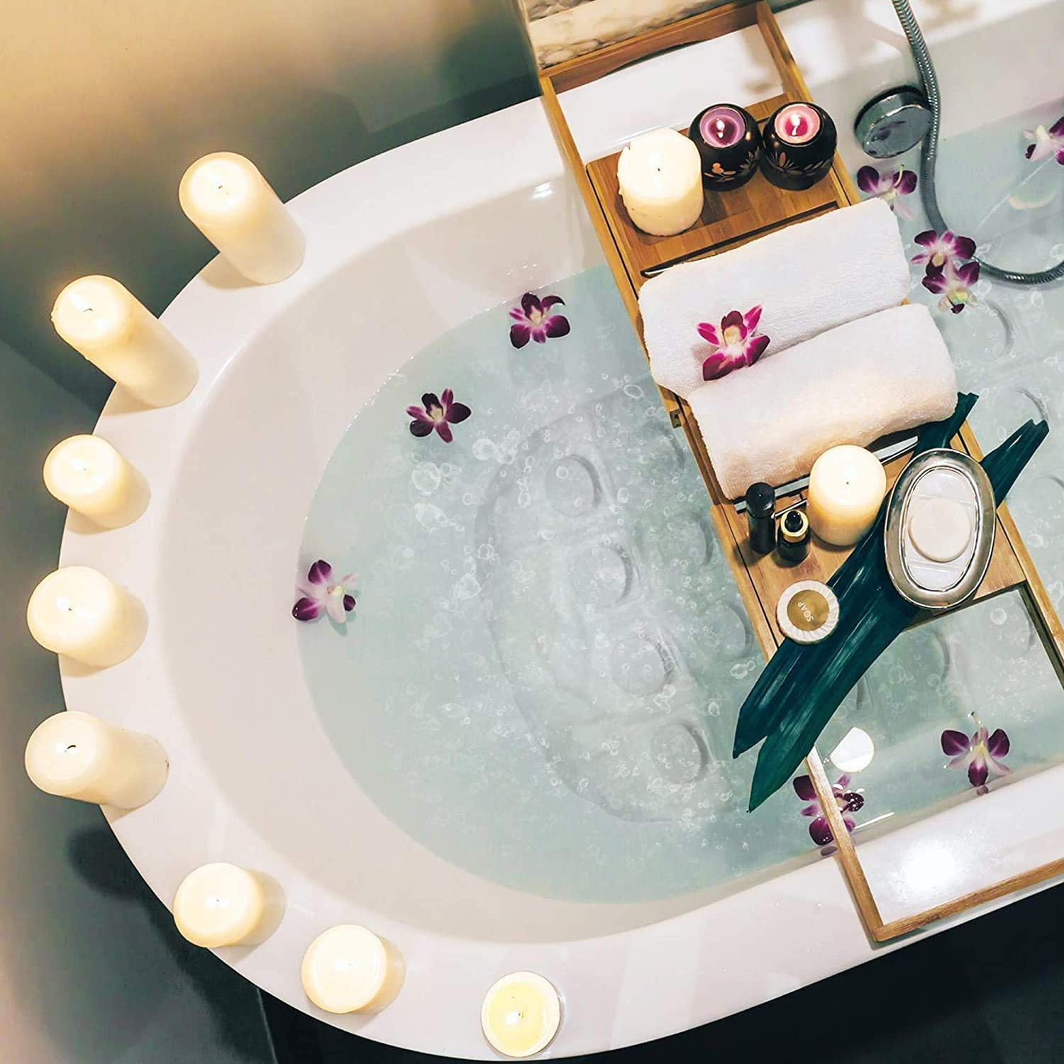 Bathtub filled with water, floating candles, and orchids. A wooden tray holds more items.