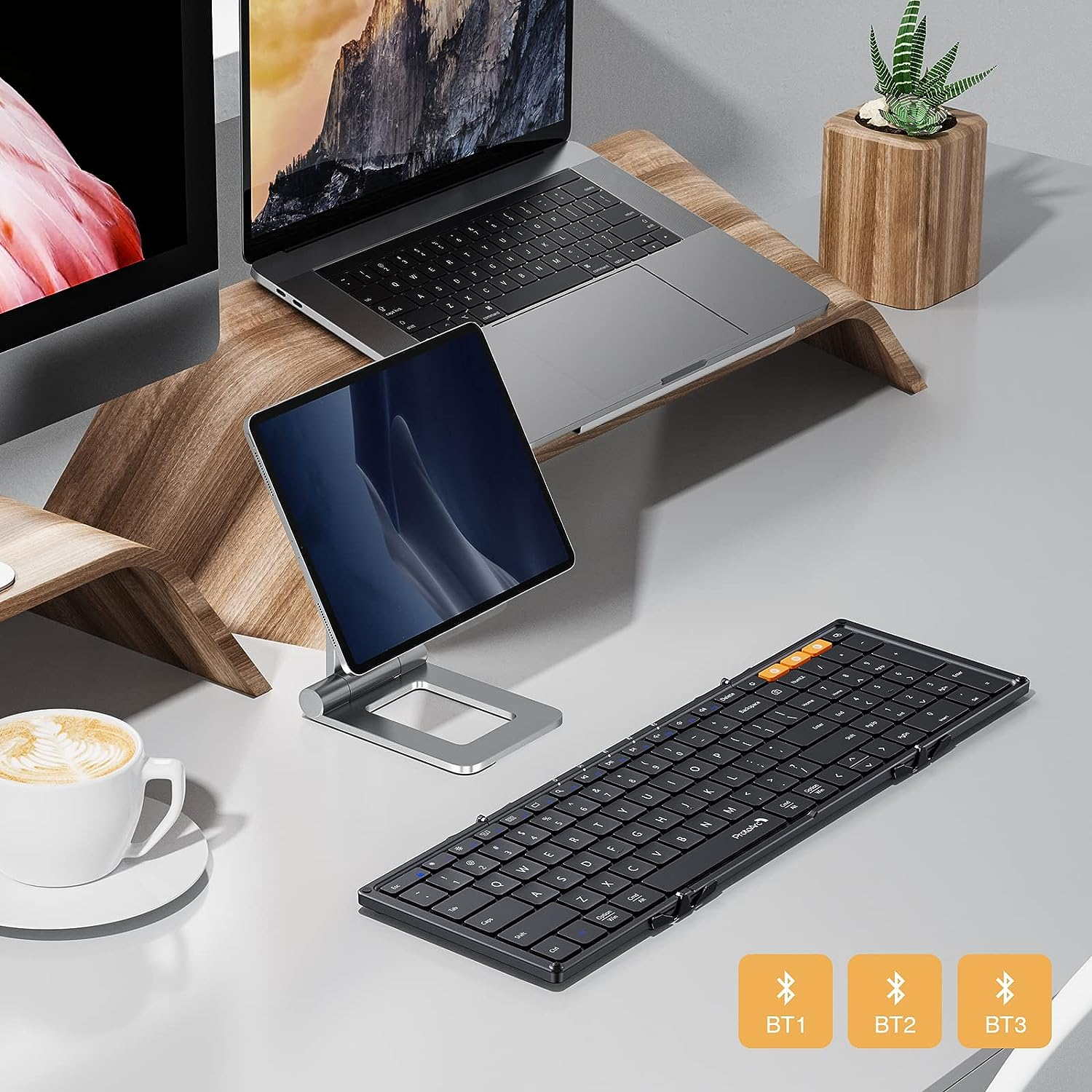 Ein Tablet auf einem Ständer, ein Laptop, eine Tastatur und eine Tasse auf einem Schreibtisch.