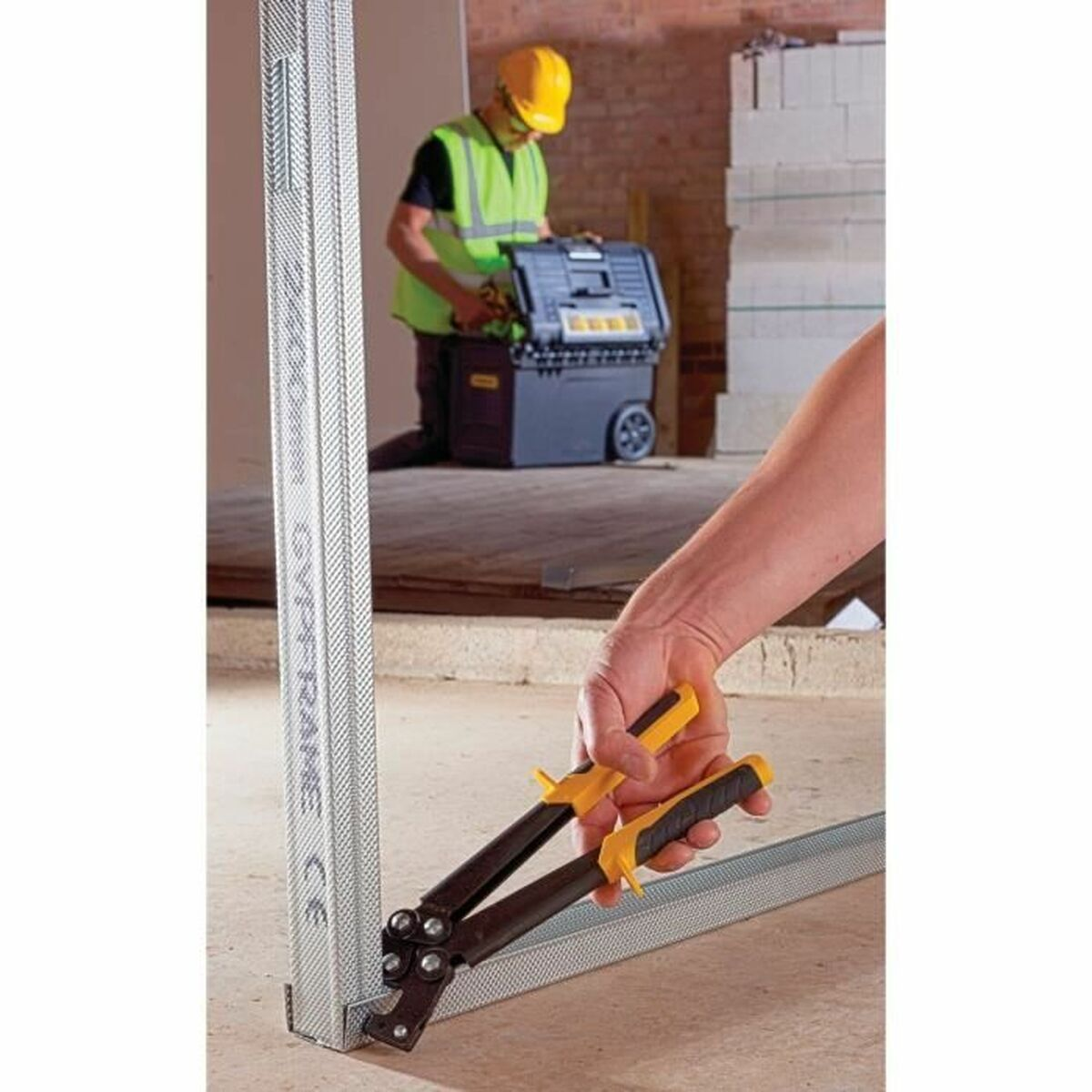 Eine Person schneidet in einer Baustelle mit Metallschneidern einen Metallstift.