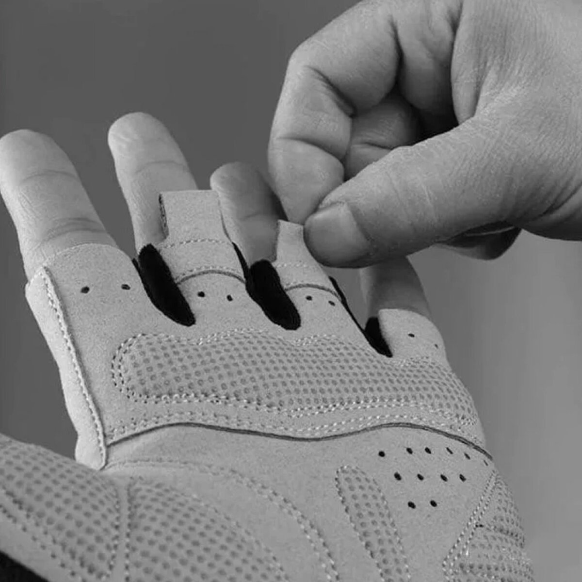 Die Hand einer Person passt einen Fingerriemen an einem hellen Mesh-Handschuh an.