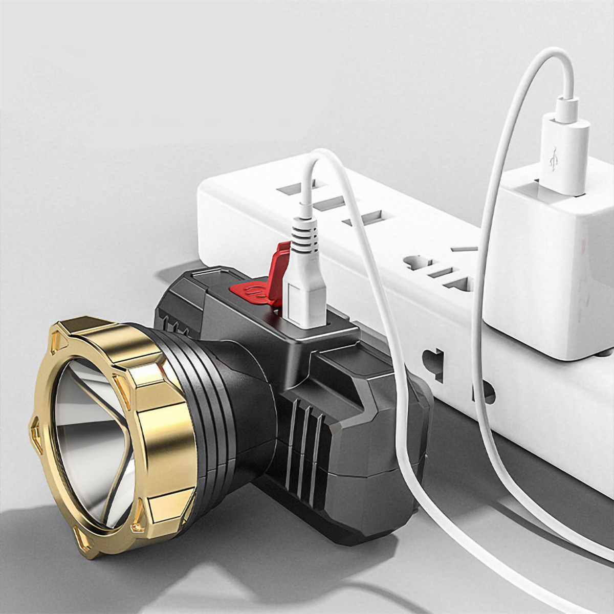 Schwarz-goldene Stirnlampe, die geladen wird, eingesteckt in eine Steckdosenleiste.