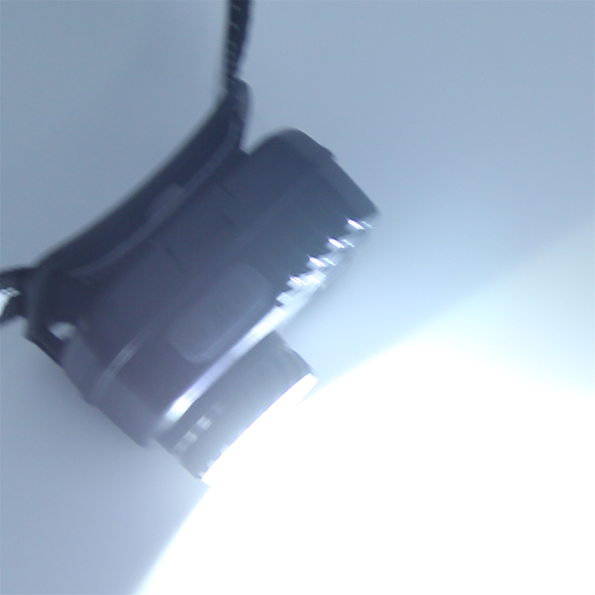 Schwarzer Scheinwerfer, der hellweißes Licht ausstrahlt. Scheinwerfer nach rechts geneigt.