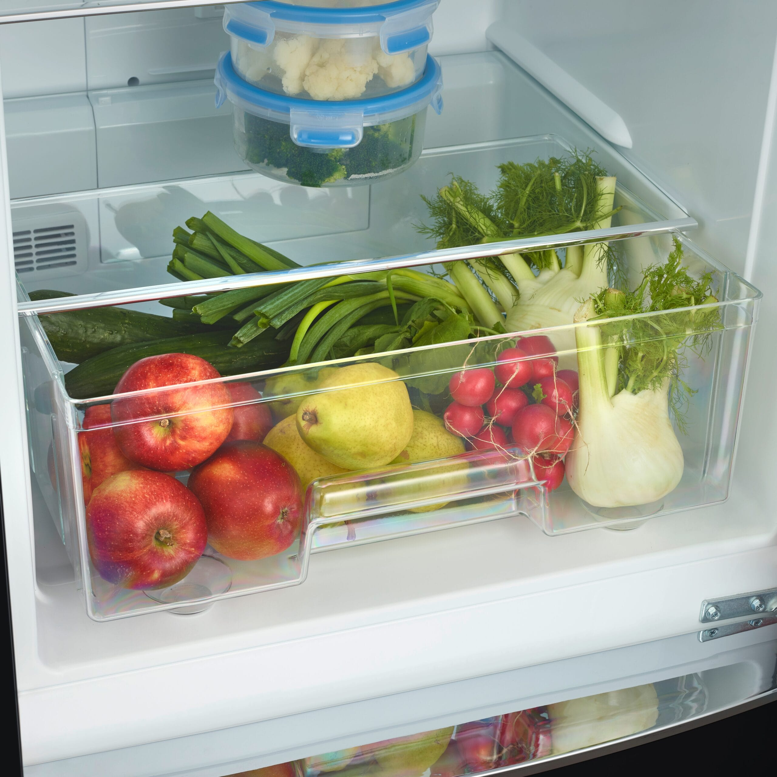 Fridge interior with fruits and vegetables in clear containers.