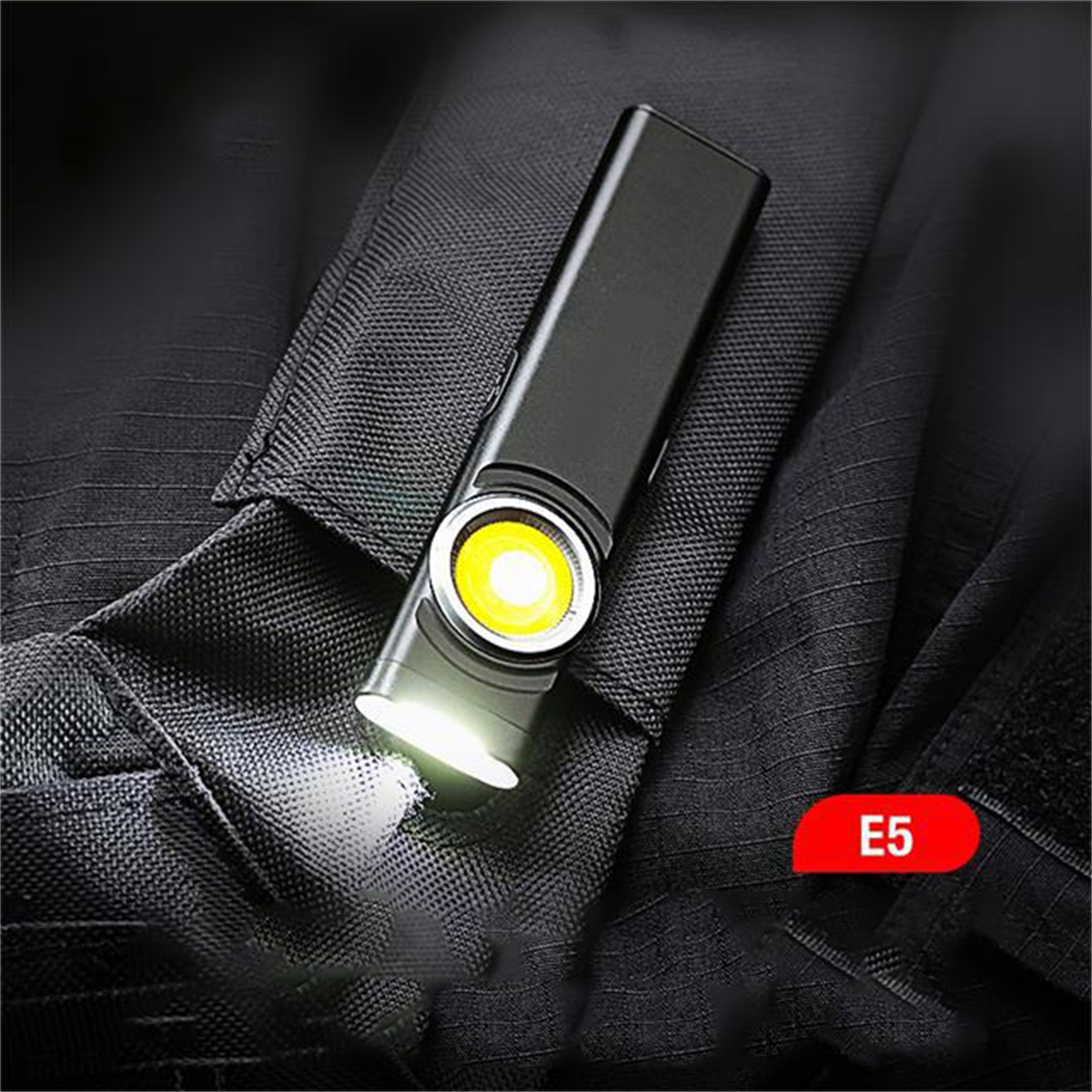 Schwarze Taschenlampe auf Jacke. Licht ist an. Das Etikett E5 ist in der Ecke.