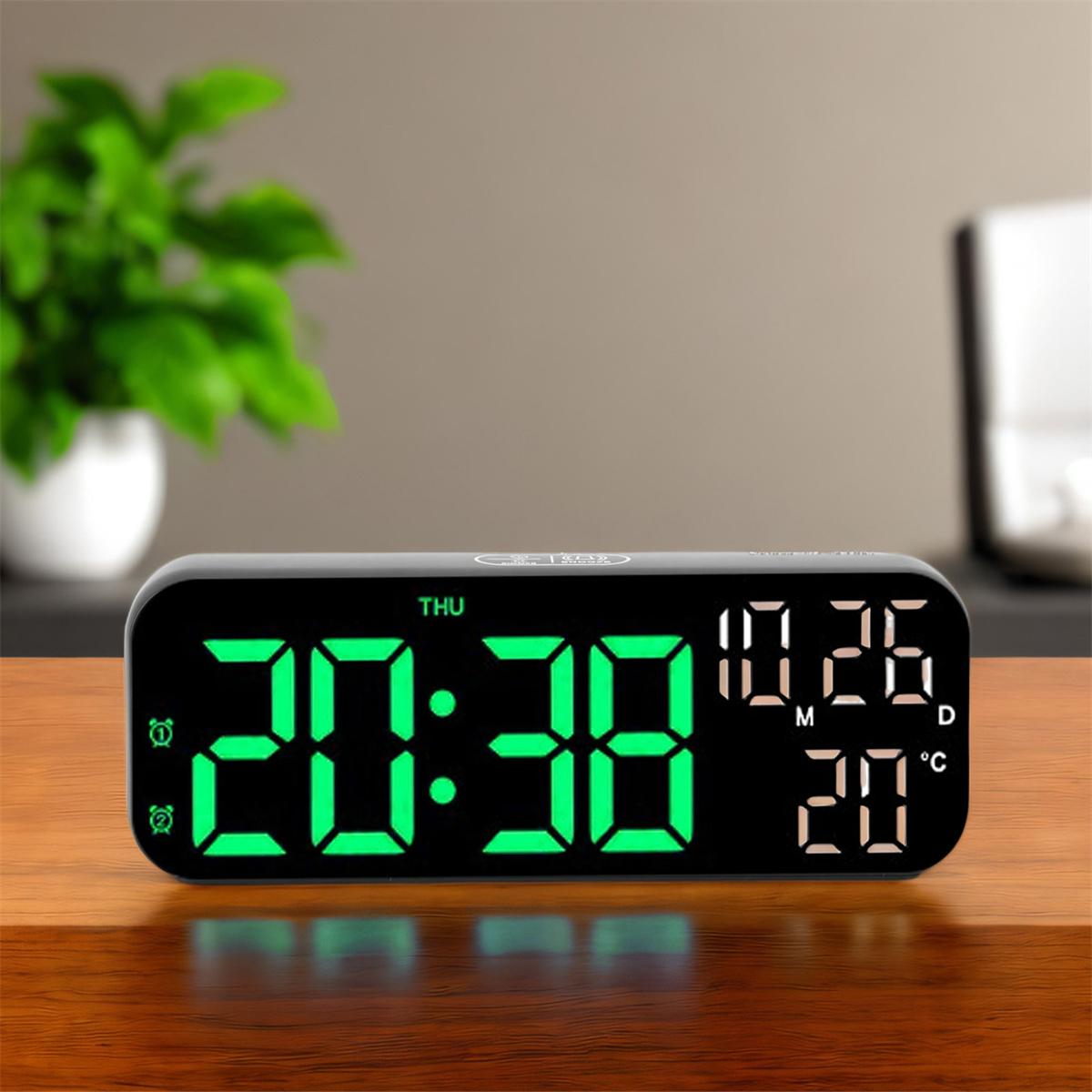 Eine schwarze Digitaluhr mit grünen Ziffern auf einem Holztisch. Grüne Pflanze im Hintergrund.