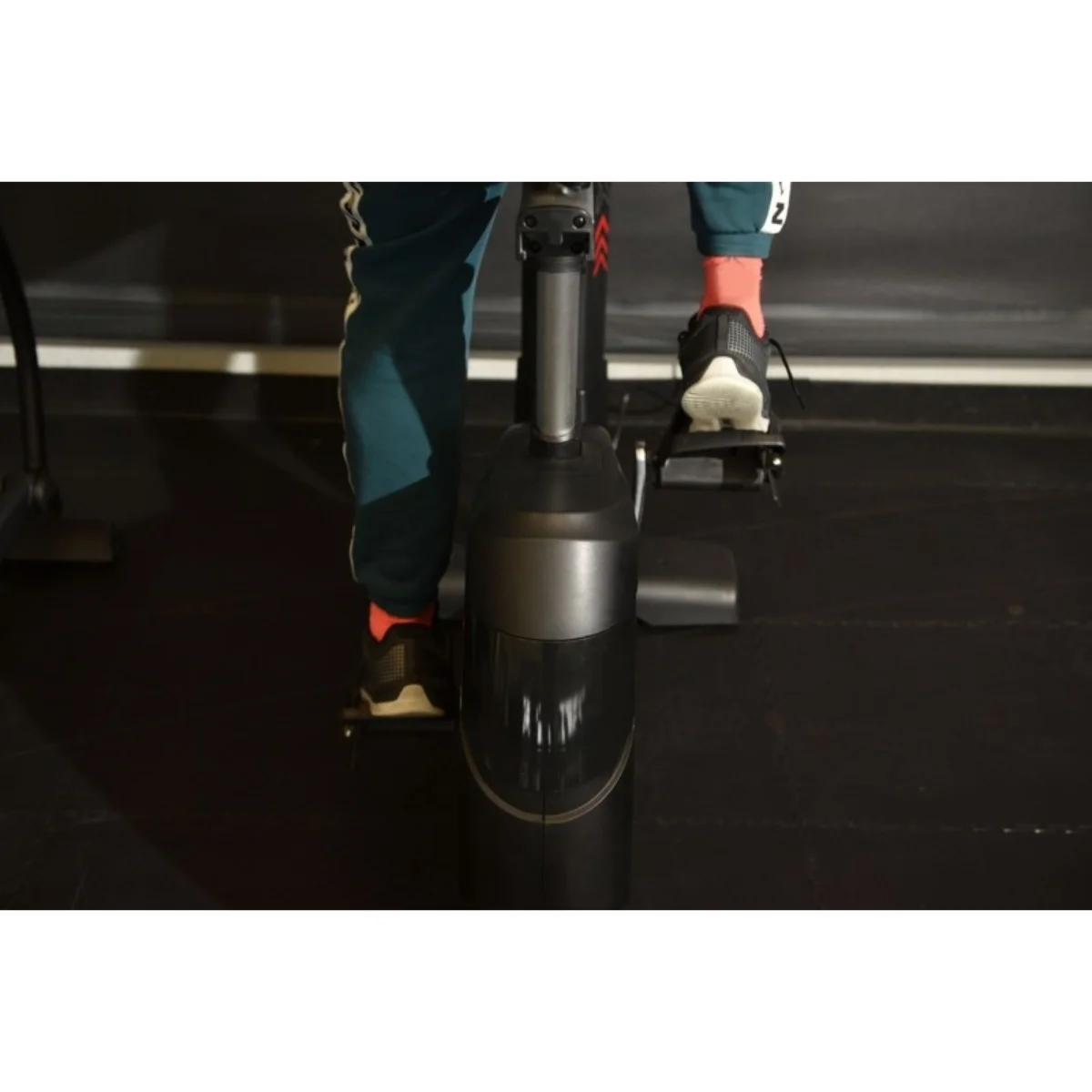 Une personne sur un vélo stationnaire, pieds sur les pédales, dans une salle de sport.