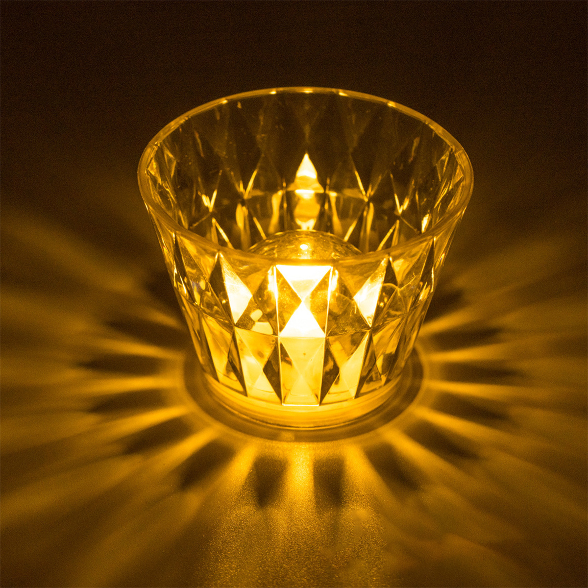 Ein leuchtender Kerzenhalter aus Glas mit Diamantenmuster und Licht.