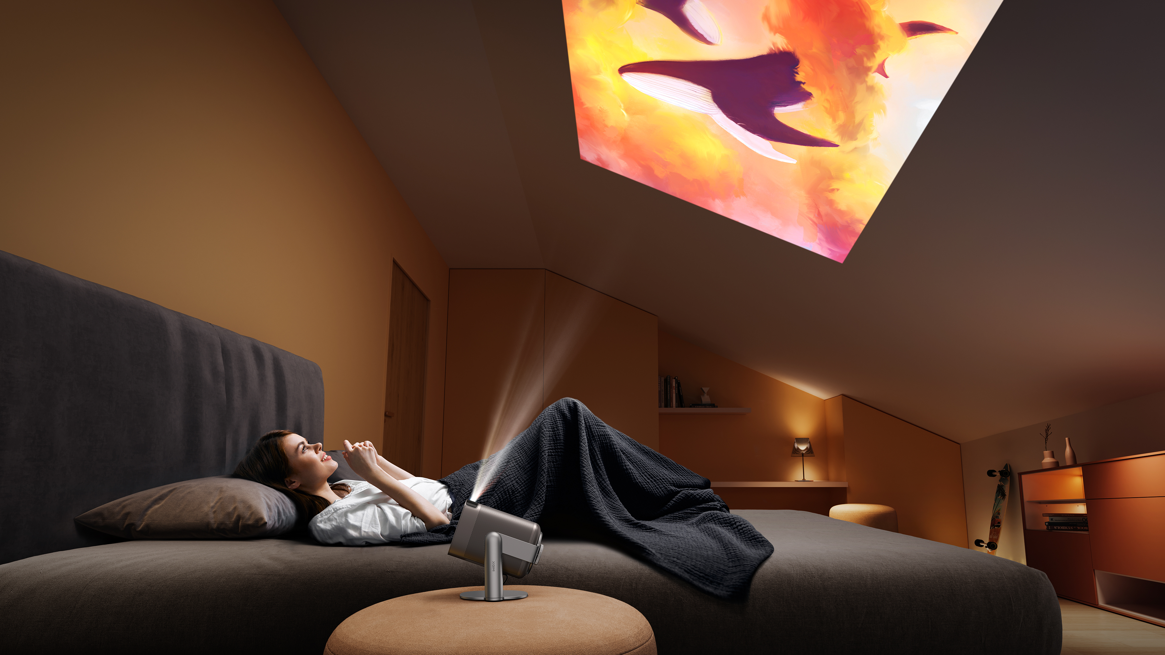 A woman lying on a bed watching a projected image of whales on the ceiling.