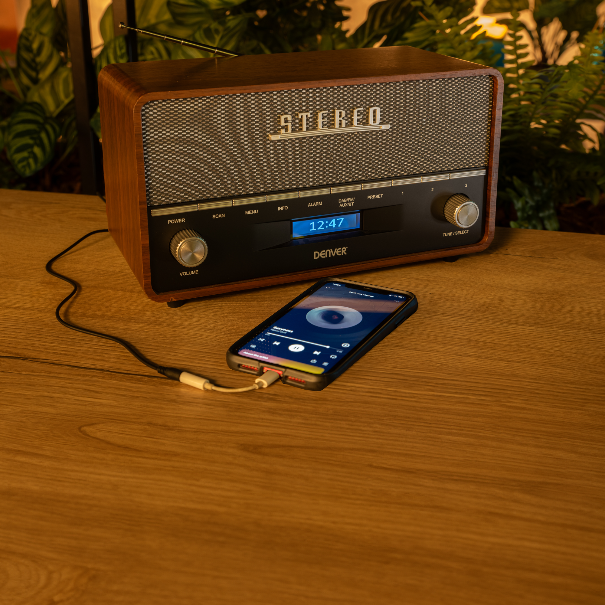 Radio w stylu vintage z podłączonym telefonem, na drewnianej powierzchni.