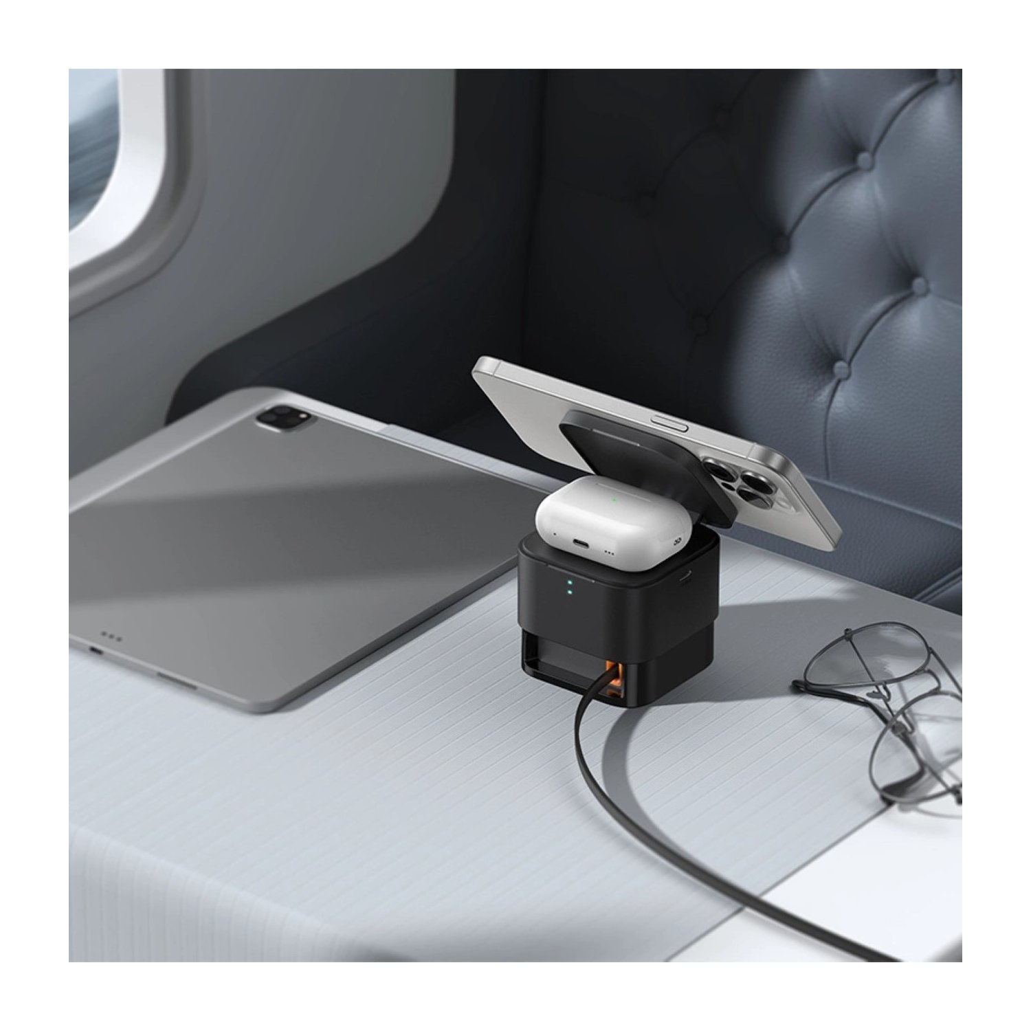 Estación de carga negra con teléfono, auriculares y tableta en mesa.