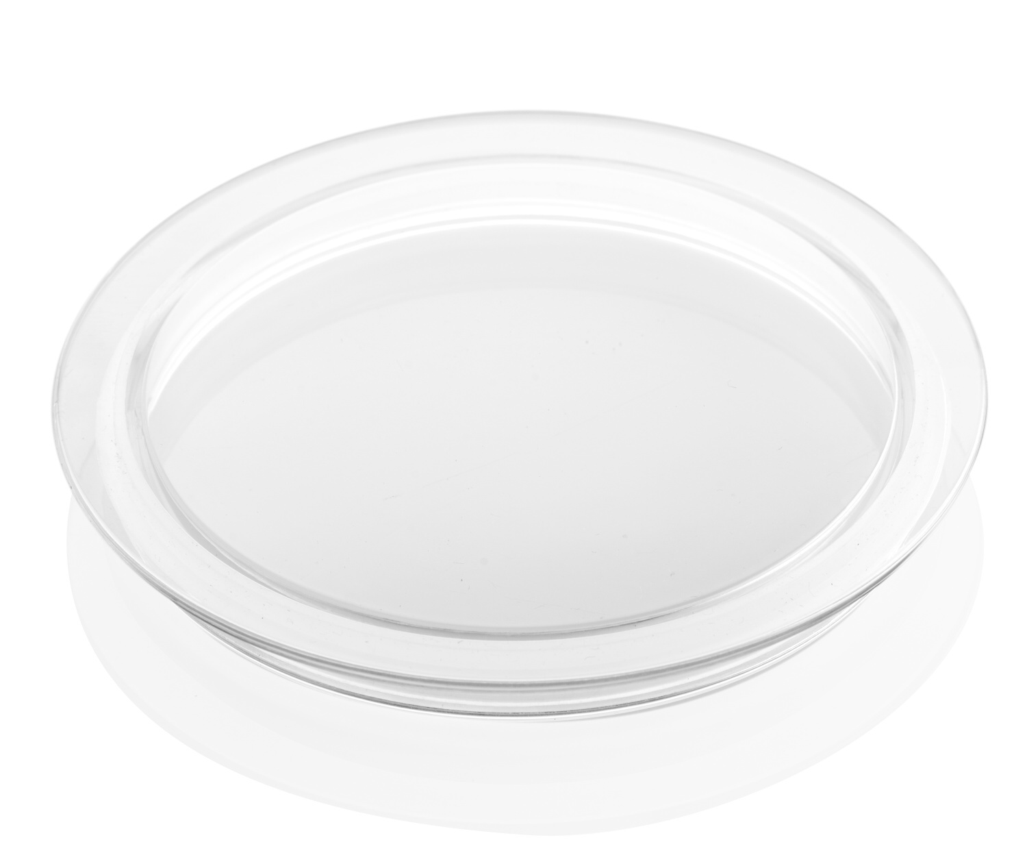 Przezroczysta szklana pokrywa na białej powierzchni. Lekko podniesiona krawędź, przezroczysta, okrągły kształt.