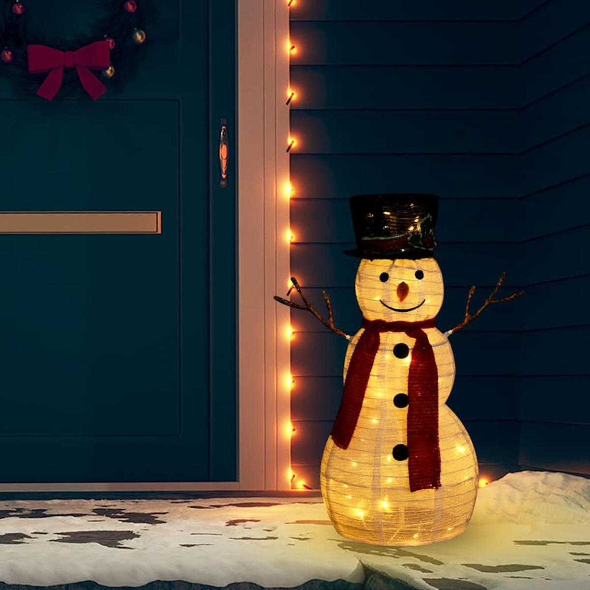 Beleuchteter Schneemann mit Zylinder, Schal und blauer Tür im Hintergrund.