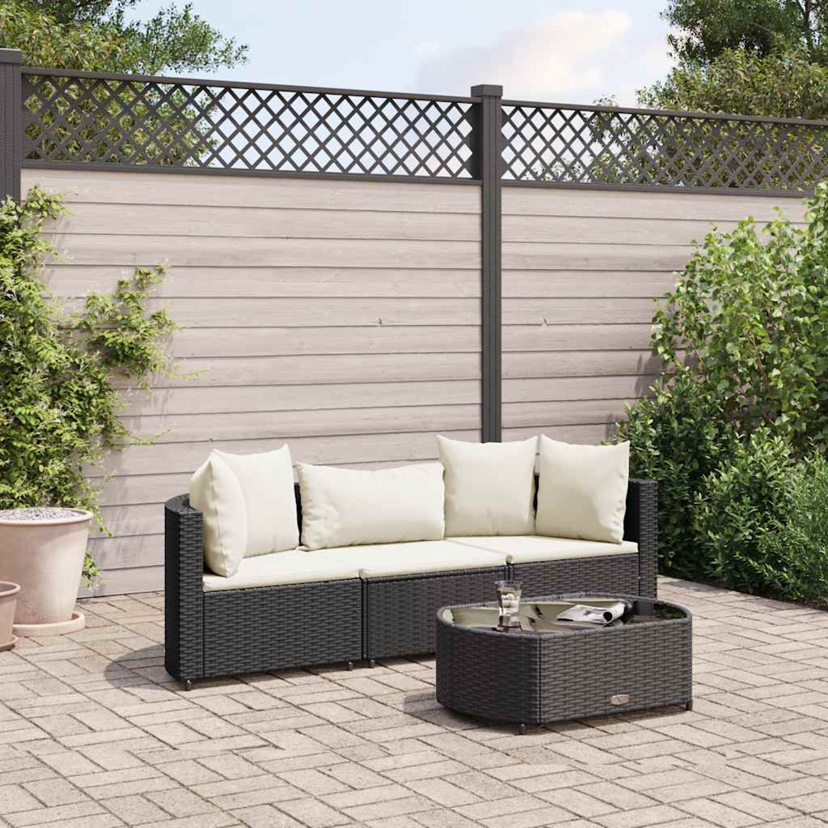 Set da patio: divano in vimini nero con cuscini color crema e tavolino abbinato su un patio in mattoni.