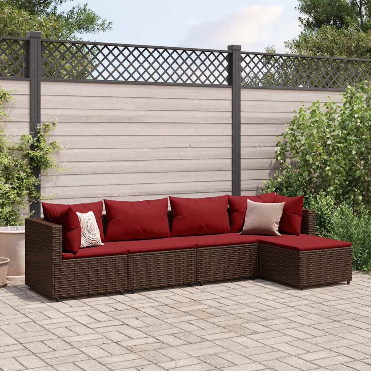 Braunes, gewebtes Outdoor-Ecksofa mit roten Kissen. Ziegel-Patio und Zaun im Hintergrund.