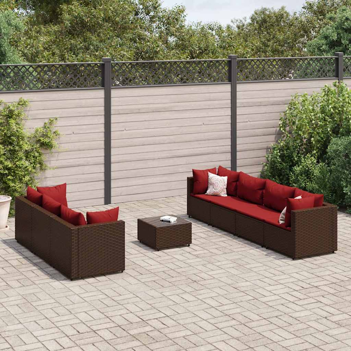 Un juego de patio al aire libre con muebles de mimbre marrón y cojines rojos, sobre adoquines.