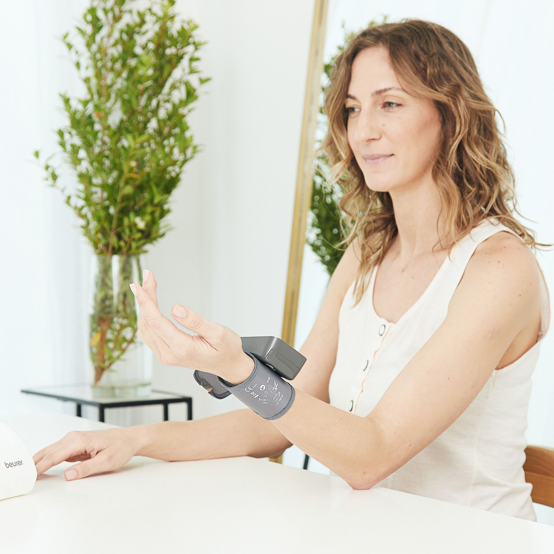 Frau mit Blutdruckmessgerät am Arm.