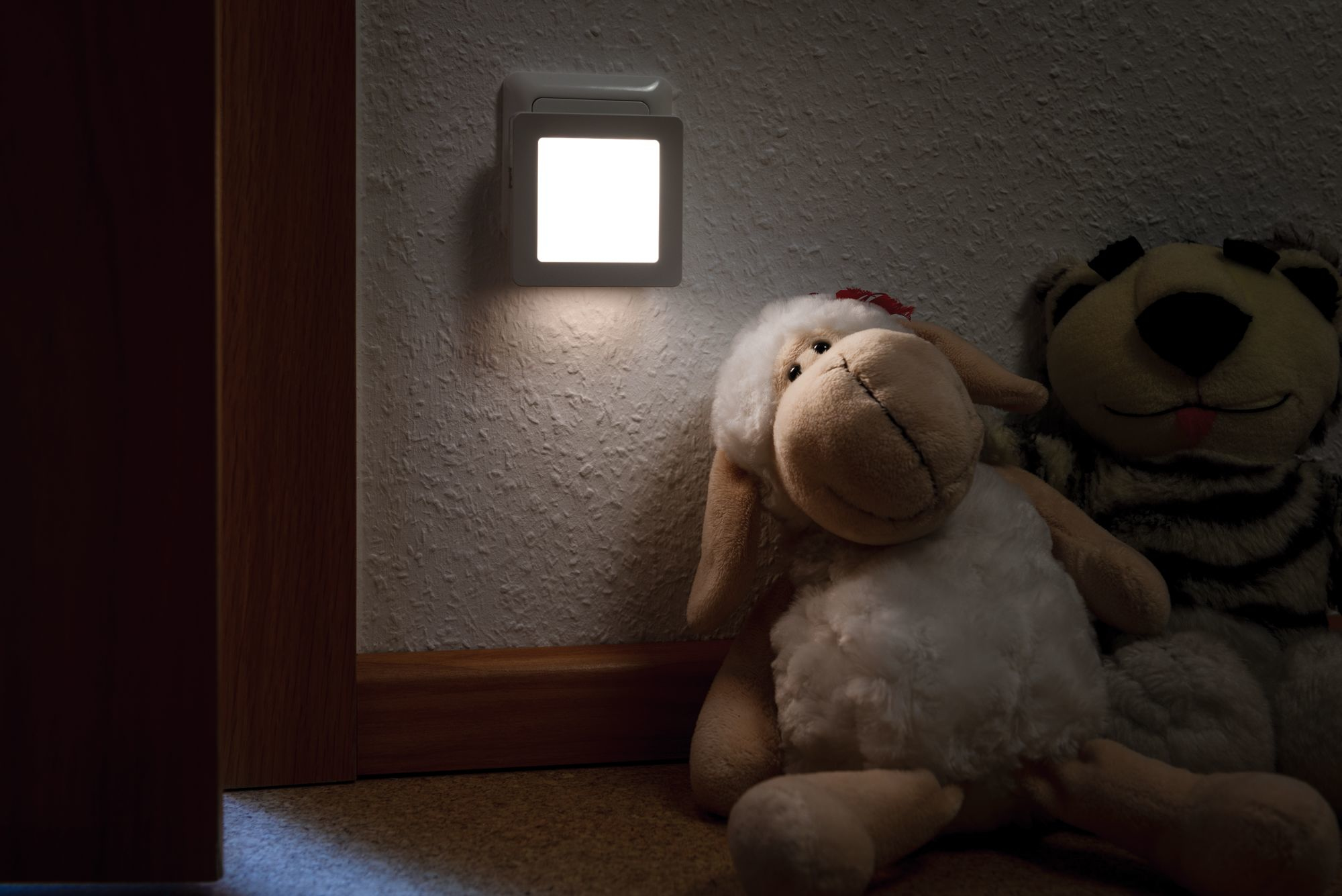 Ein Nachtlicht an der Wand, mit Stofftieren.