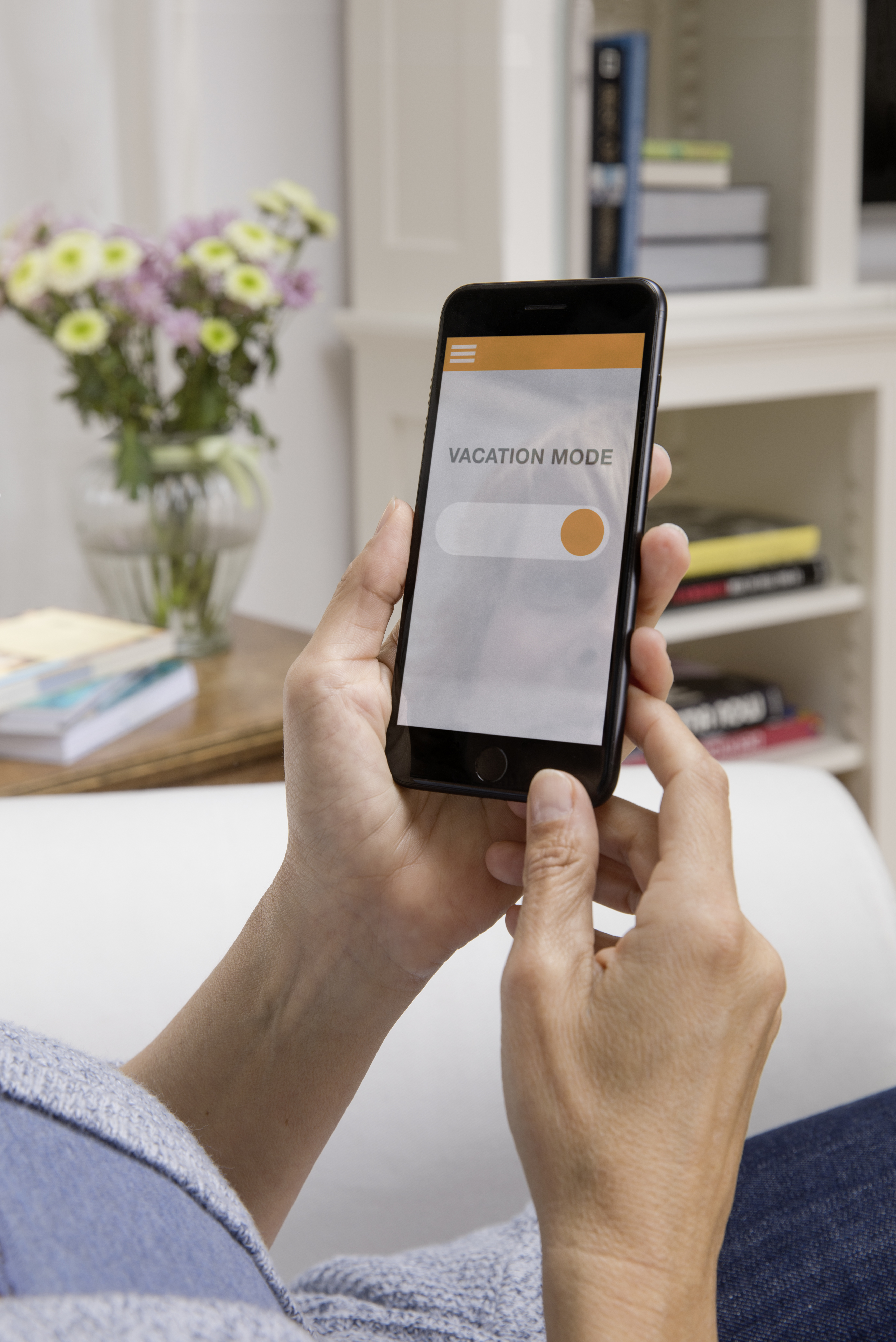 Person hält Smartphone mit Urlaubsmodus-Schalter auf dem Bildschirm.