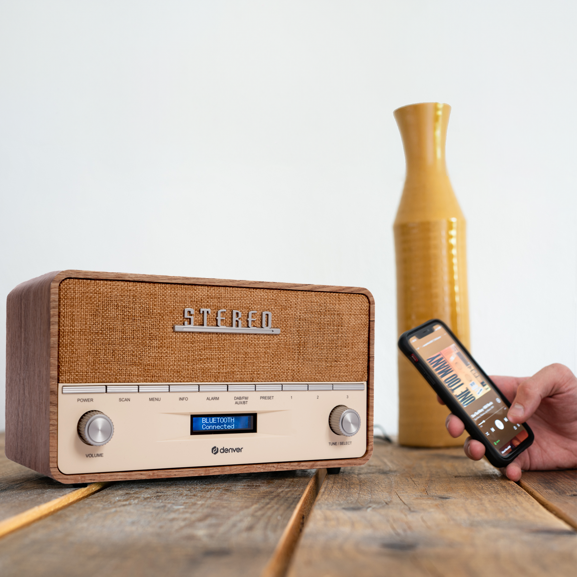 Drewniane radio w stylu retro z telefonem wyświetlającym muzykę na drewnianym stole.