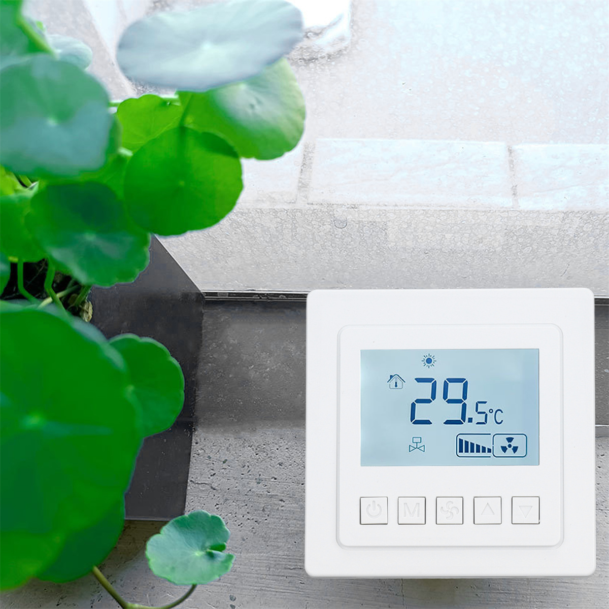 Weißer Thermostat mit 29,5°C Anzeige. Daneben eine Pflanze. Gegen eine geflieste weiße Wand.