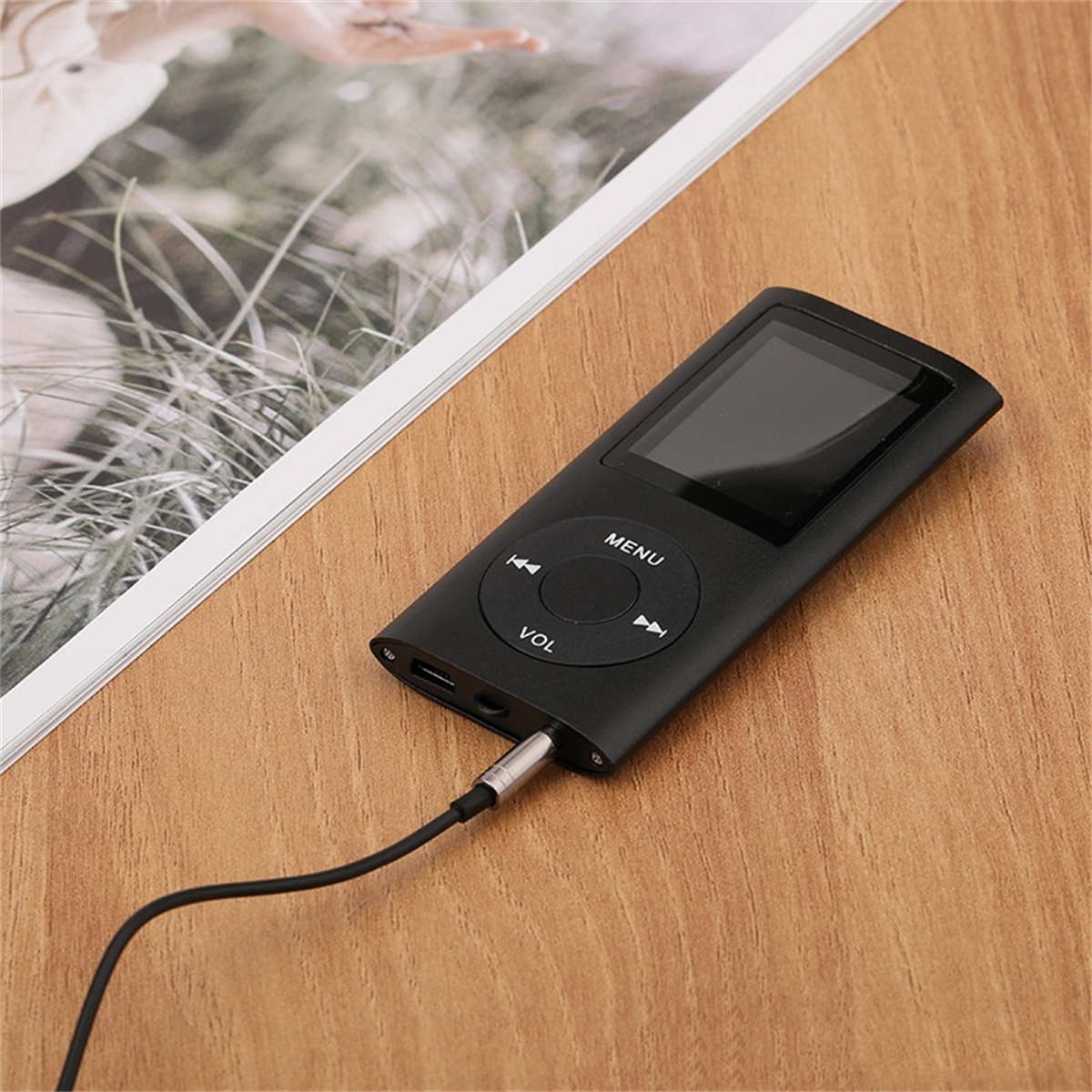 Ein schwarzer MP3-Player, der mit einem Kabel verbunden ist, auf einem Holztisch.