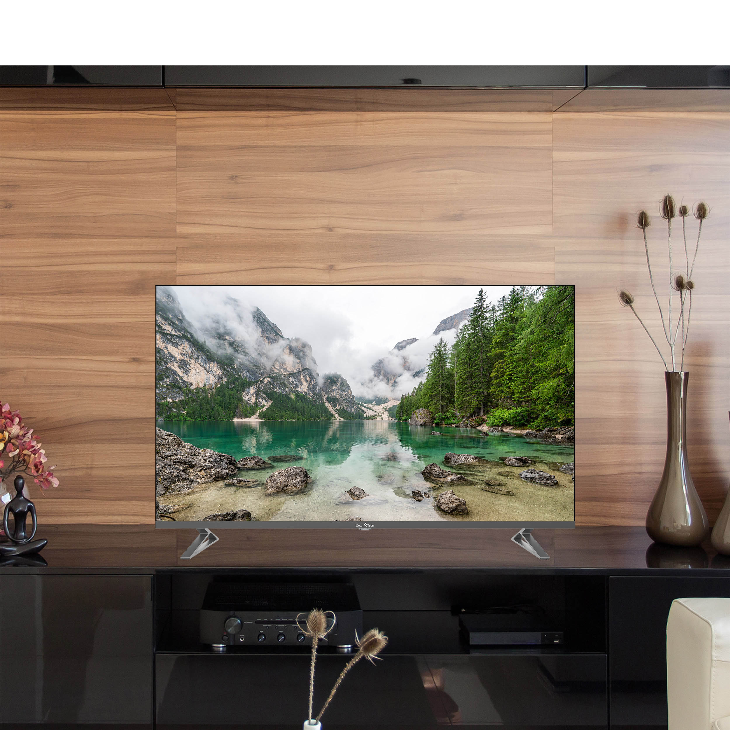 Telewizor wyświetlający scenę krajobrazową jest zamontowany na czarnej szafce z elementami dekoracyjnymi.