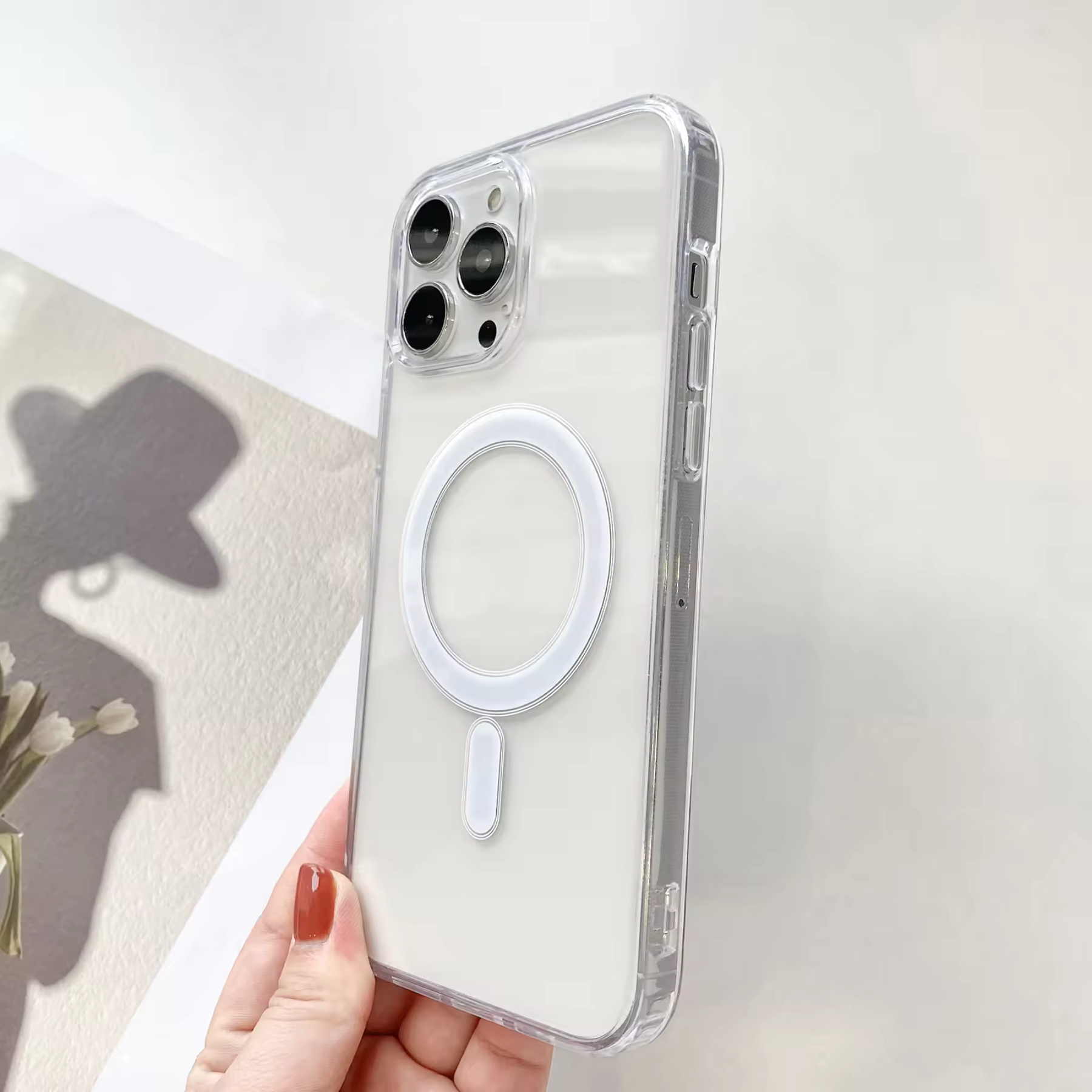 Transparente Handyhülle mit weißem Magnetring. Hand hält Hülle. Hintergrund ist verschwommen.