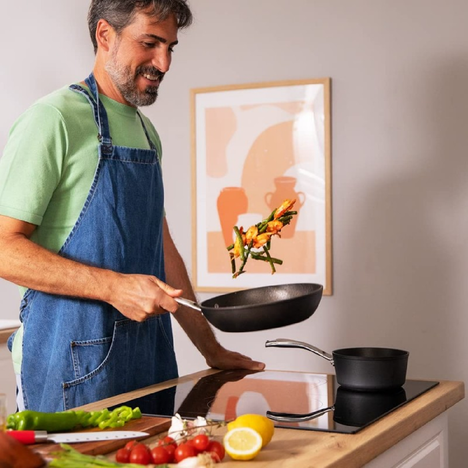 Een man die in de keuken kookt, eten omslaat in een pan, met groenten op het aanrecht.