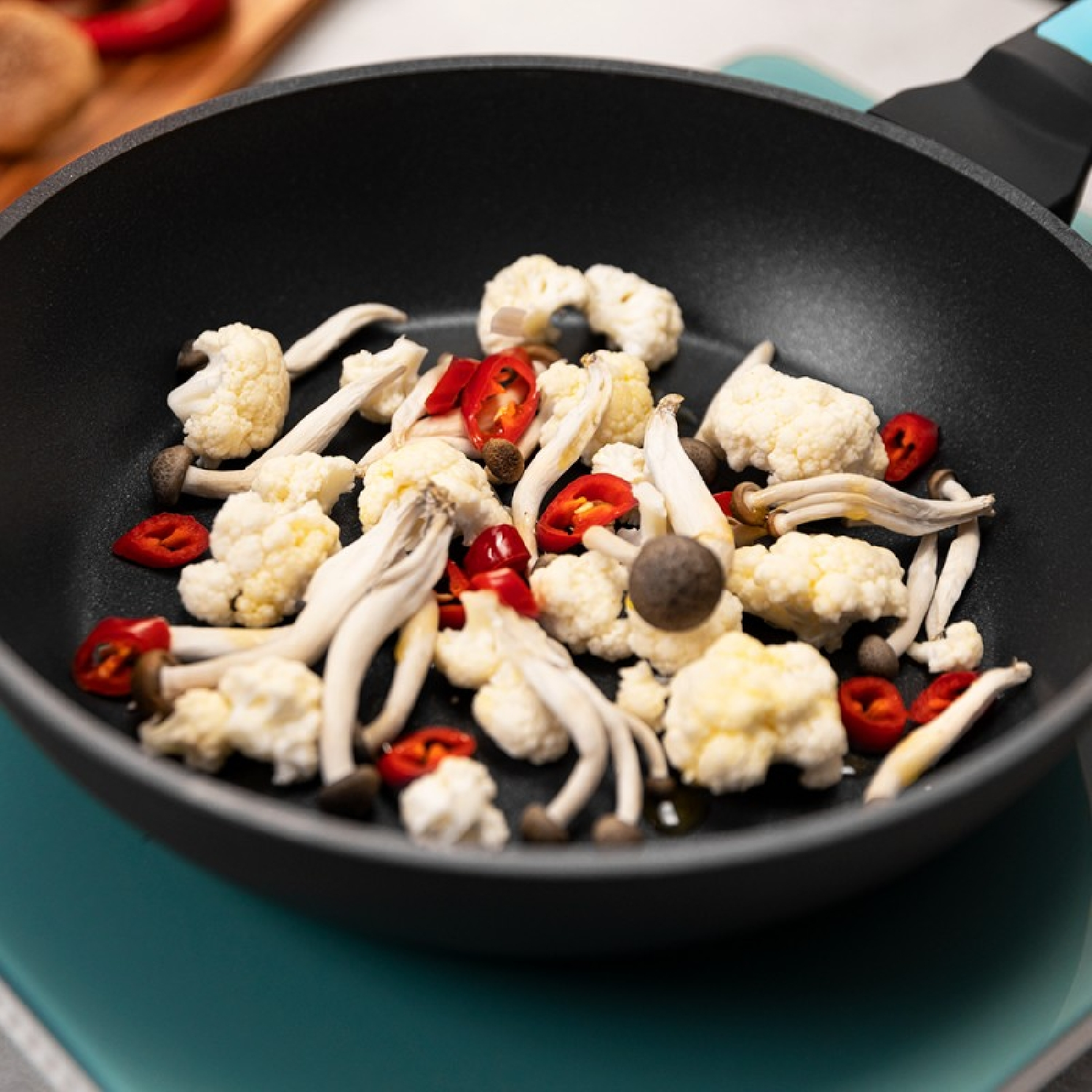 Czarna patelnia z kalafiorem, grzybami i czerwoną papryką.
