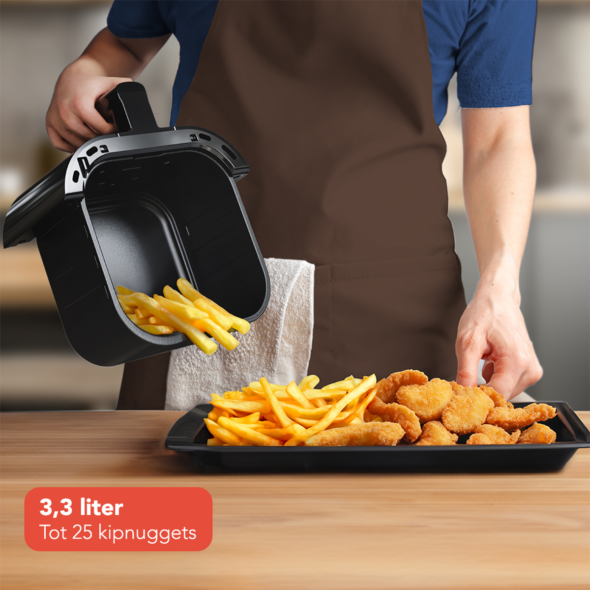 Man holding a black fryer basket with fries, next to a tray of nuggets, brown apron.