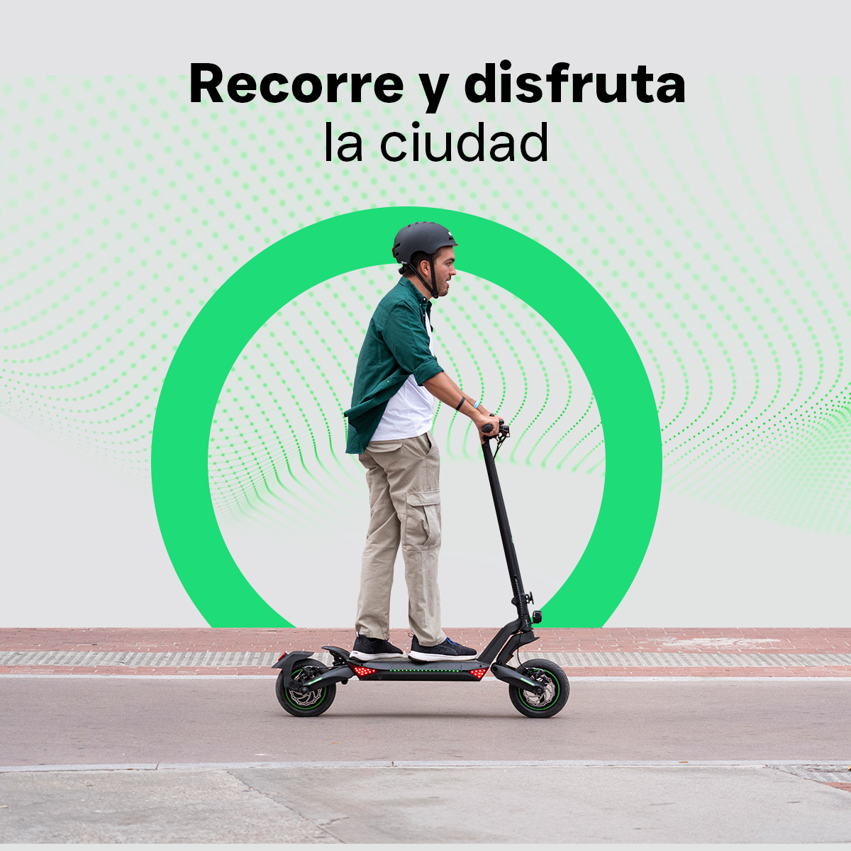 Un hombre con camisa verde y casco monta un patinete eléctrico en una calle.