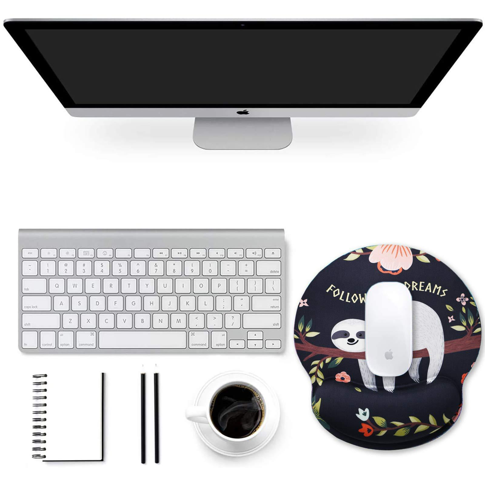 Espace de travail avec ordinateur, clavier, souris sur un tapis, carnet, stylos et café.