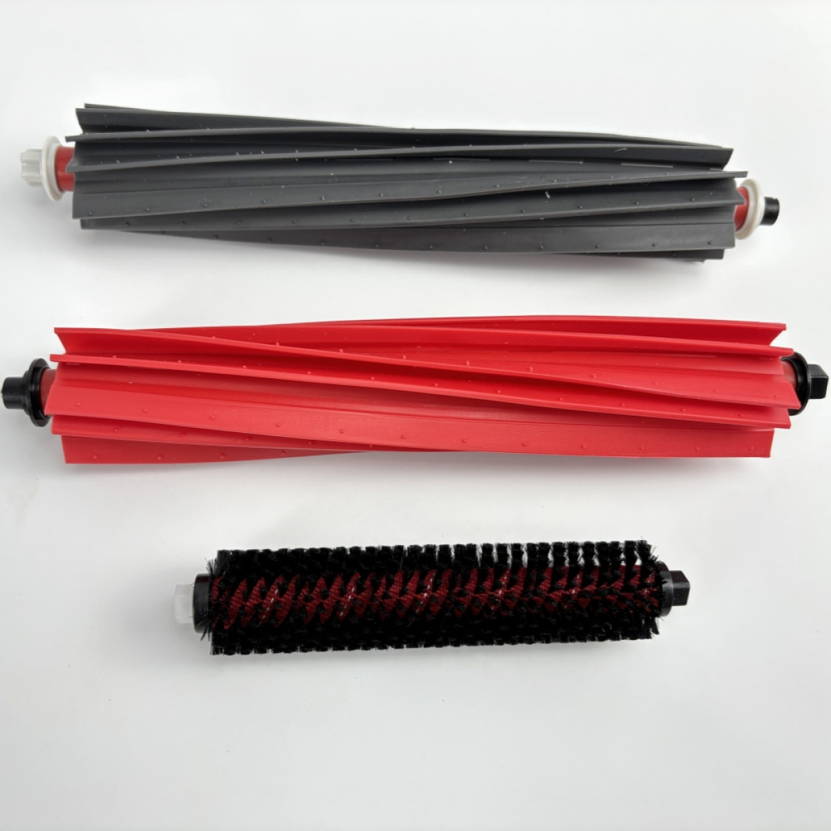 Trzy wałki szczotki do odkurzacza: szary, czerwony i czarny. Wszystkie cylindryczne z włosiem.