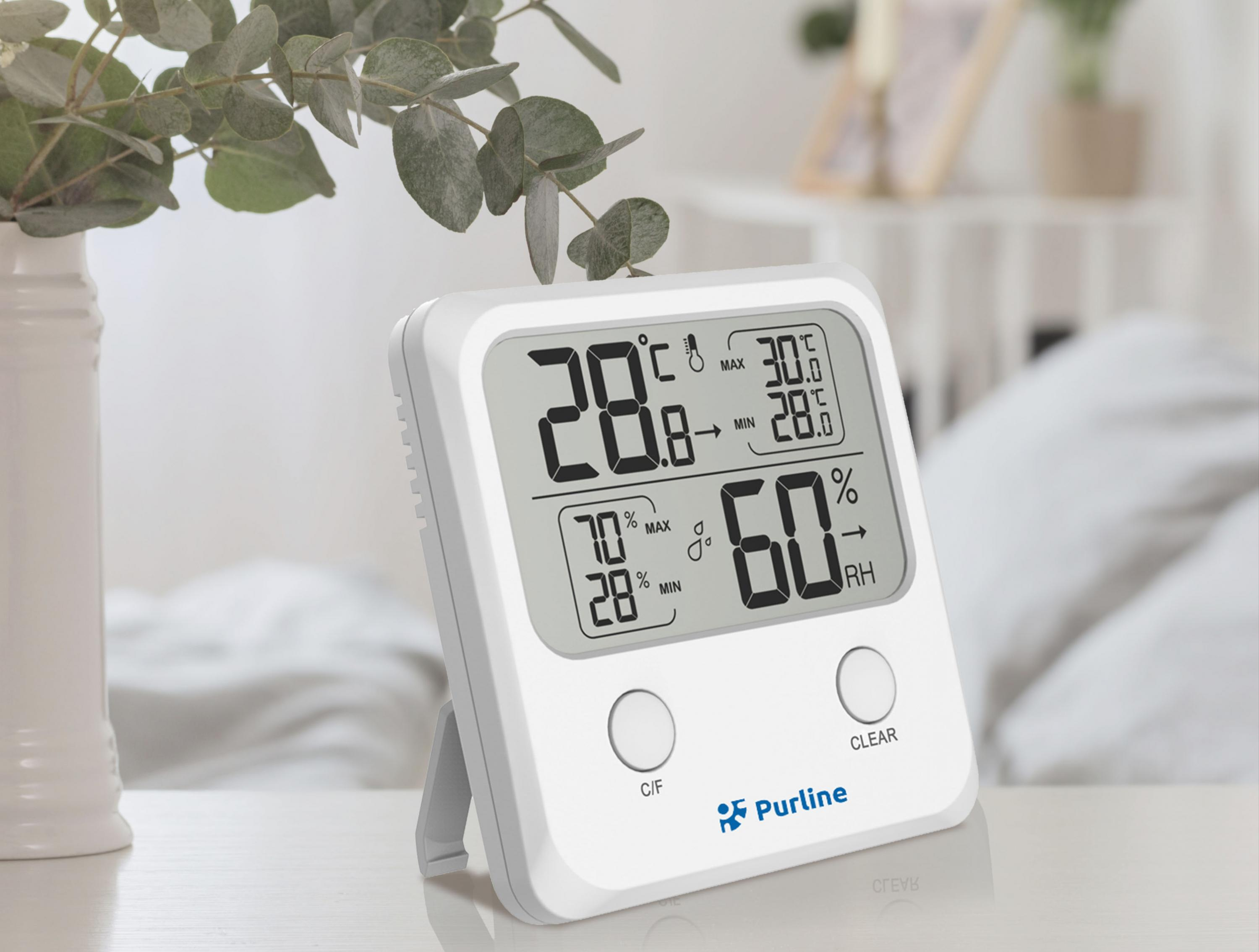 Un termómetro digital blanco muestra lecturas de temperatura y humedad.