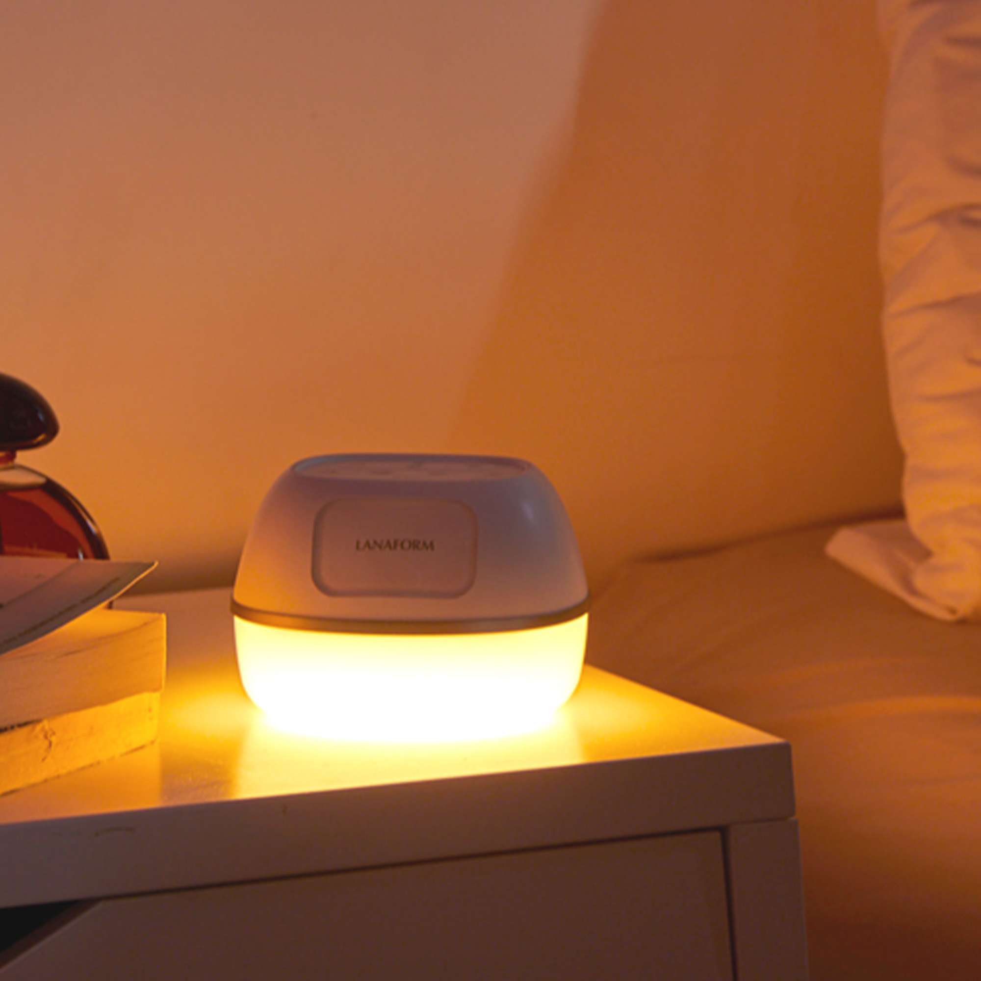 Glowing white lamp on a nightstand, illuminating a warm-toned room.