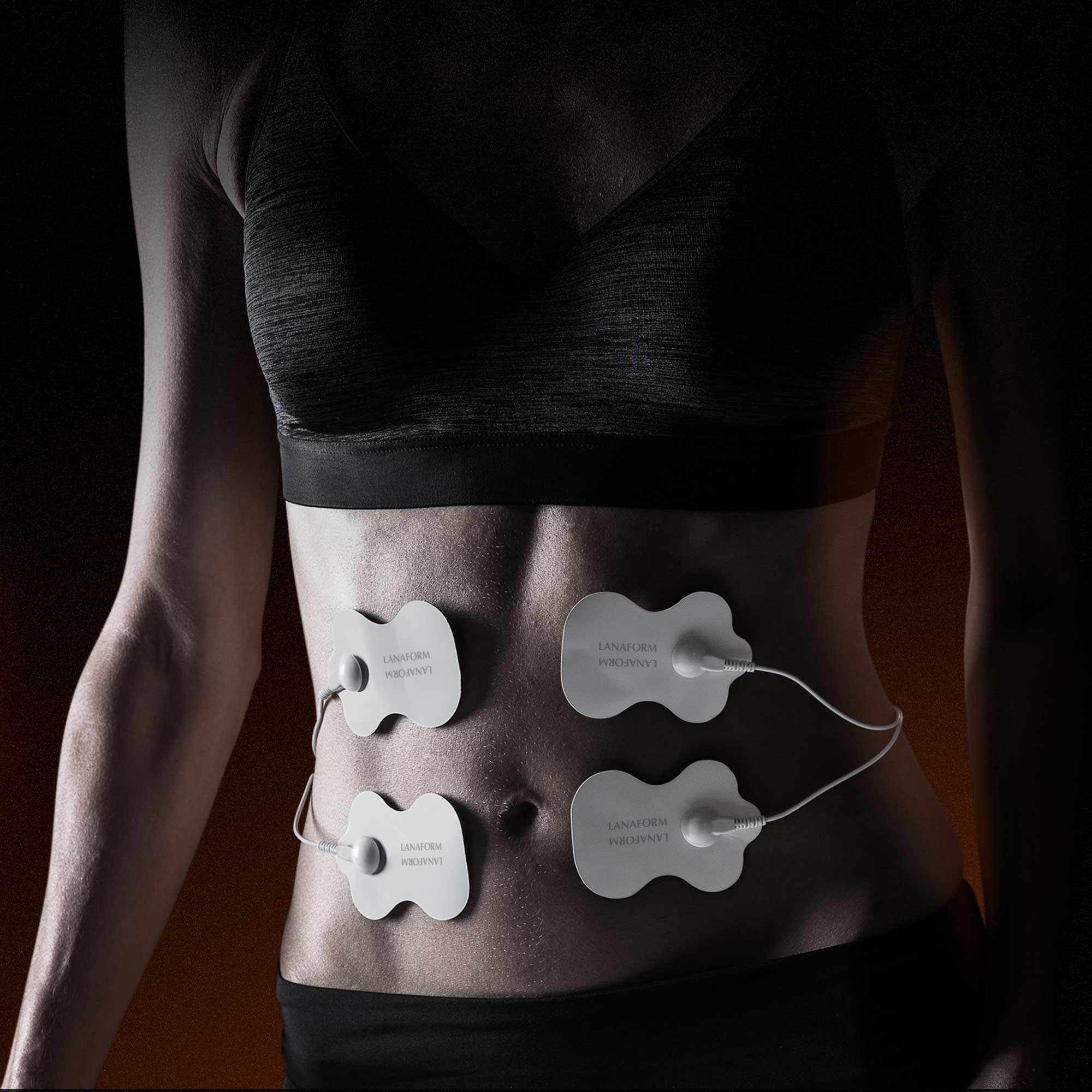 Vrouwelijk torso met elektroden van een Lanaform-apparaat op haar buik.
