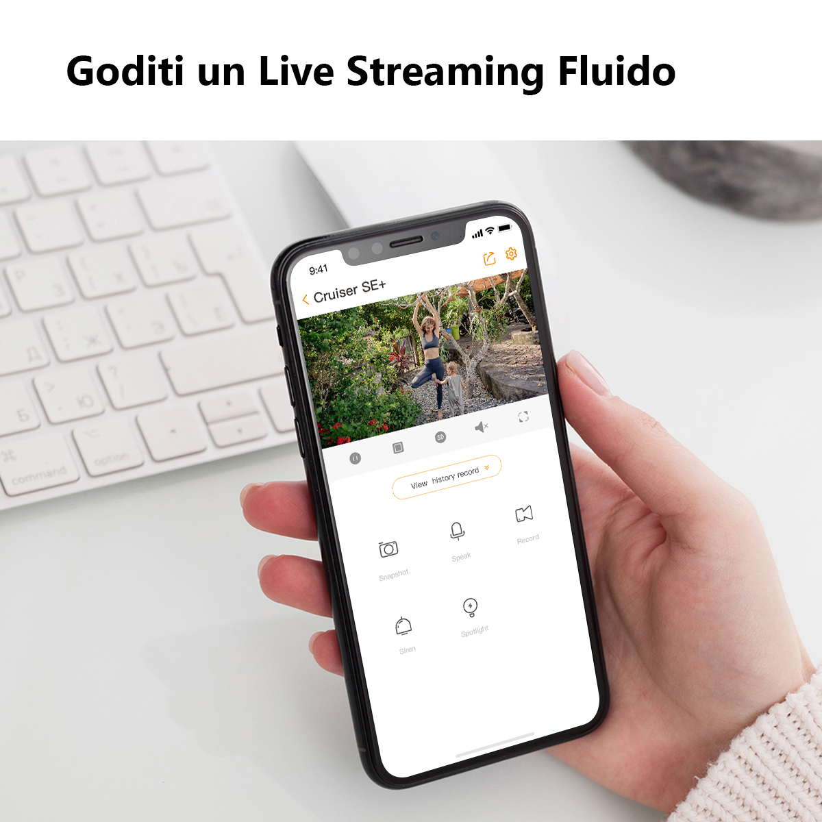 Osoba trzymająca telefon pokazujący transmisję na żywo z kamery bezpieczeństwa. Klawiatura w tle.
