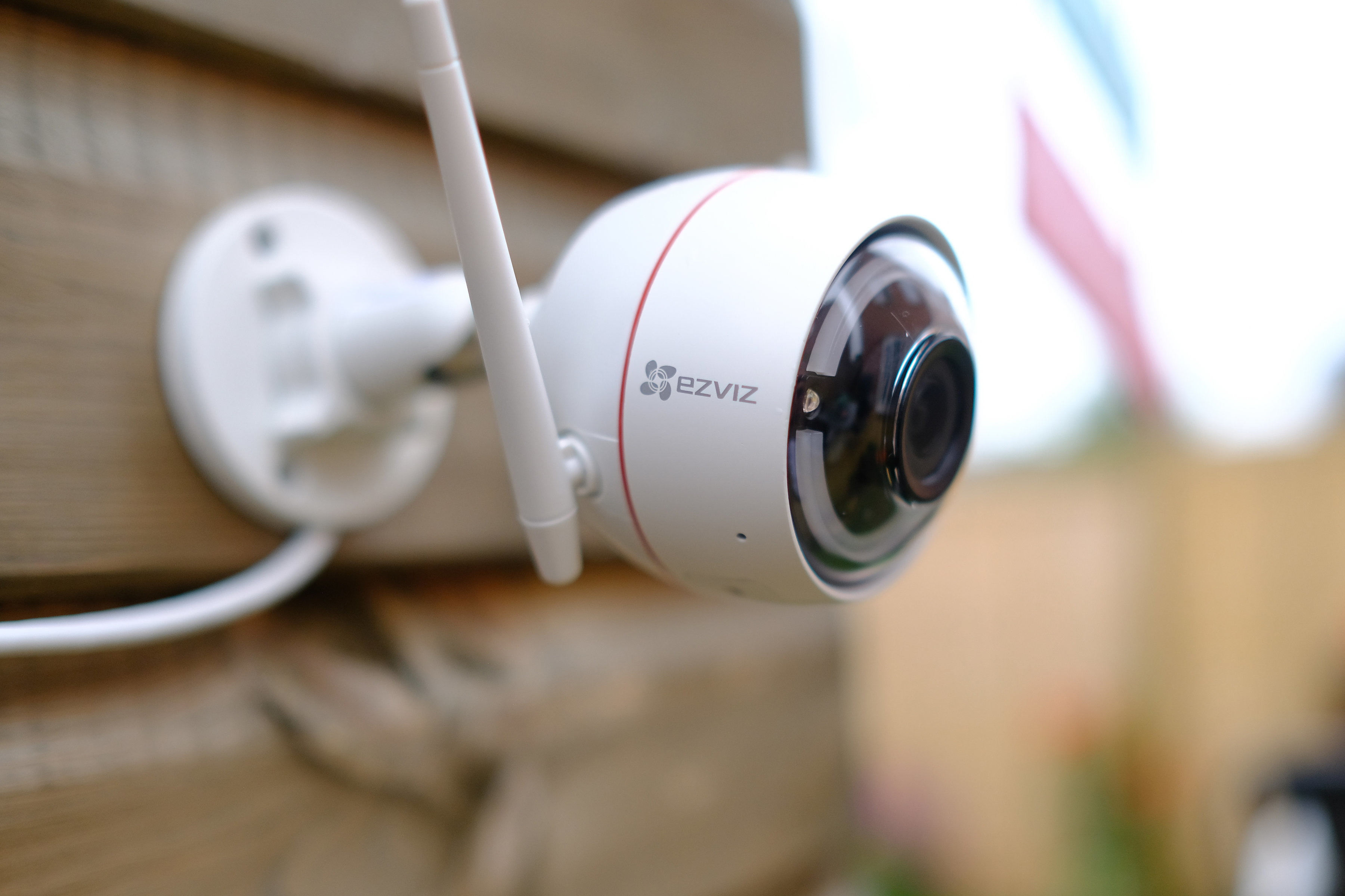 Telecamera di sicurezza bianca e rossa montata su una parete di legno. La telecamera ha una forma arrotondata.