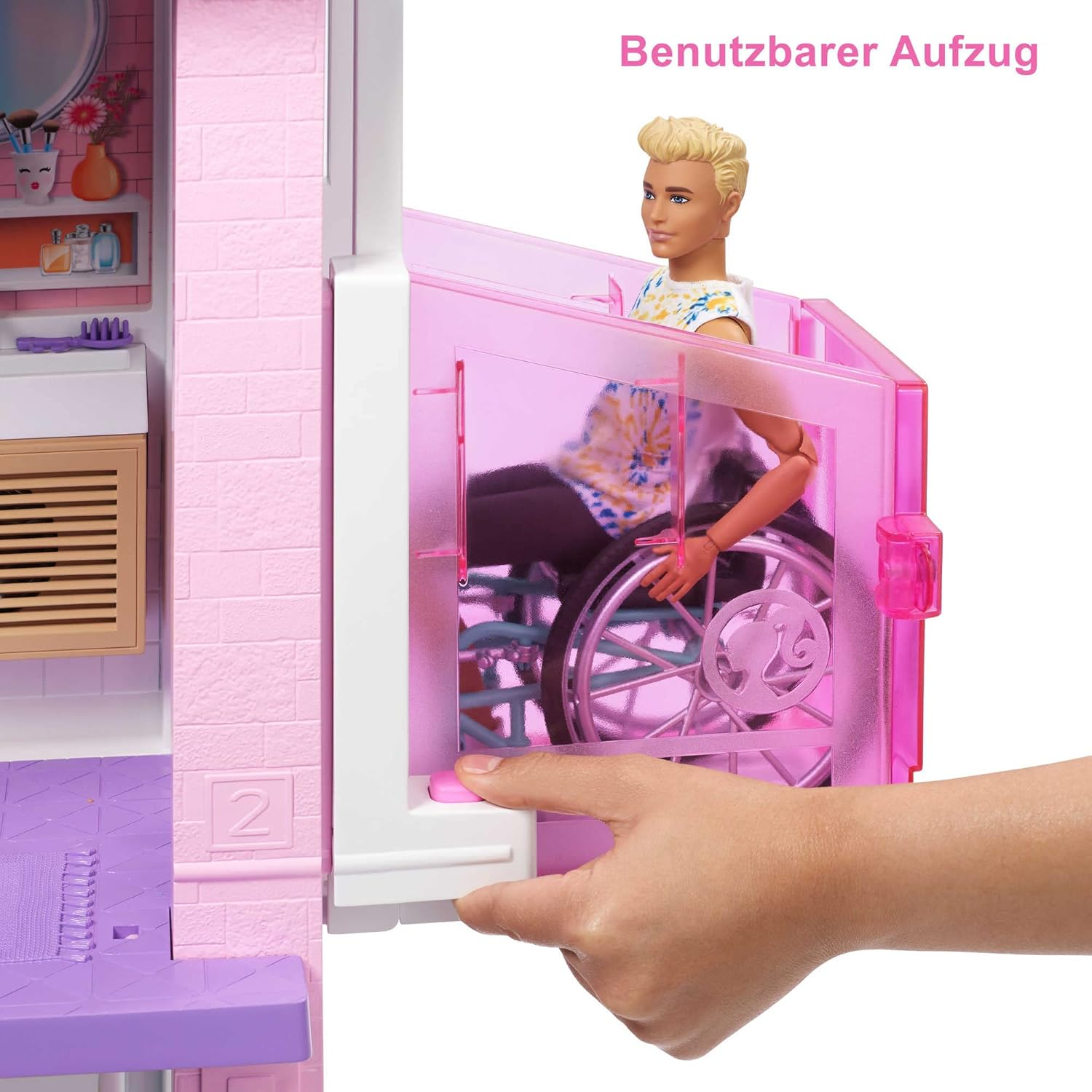 Puppe und Ken im Rollstuhl in einem rosa Puppenhaus.