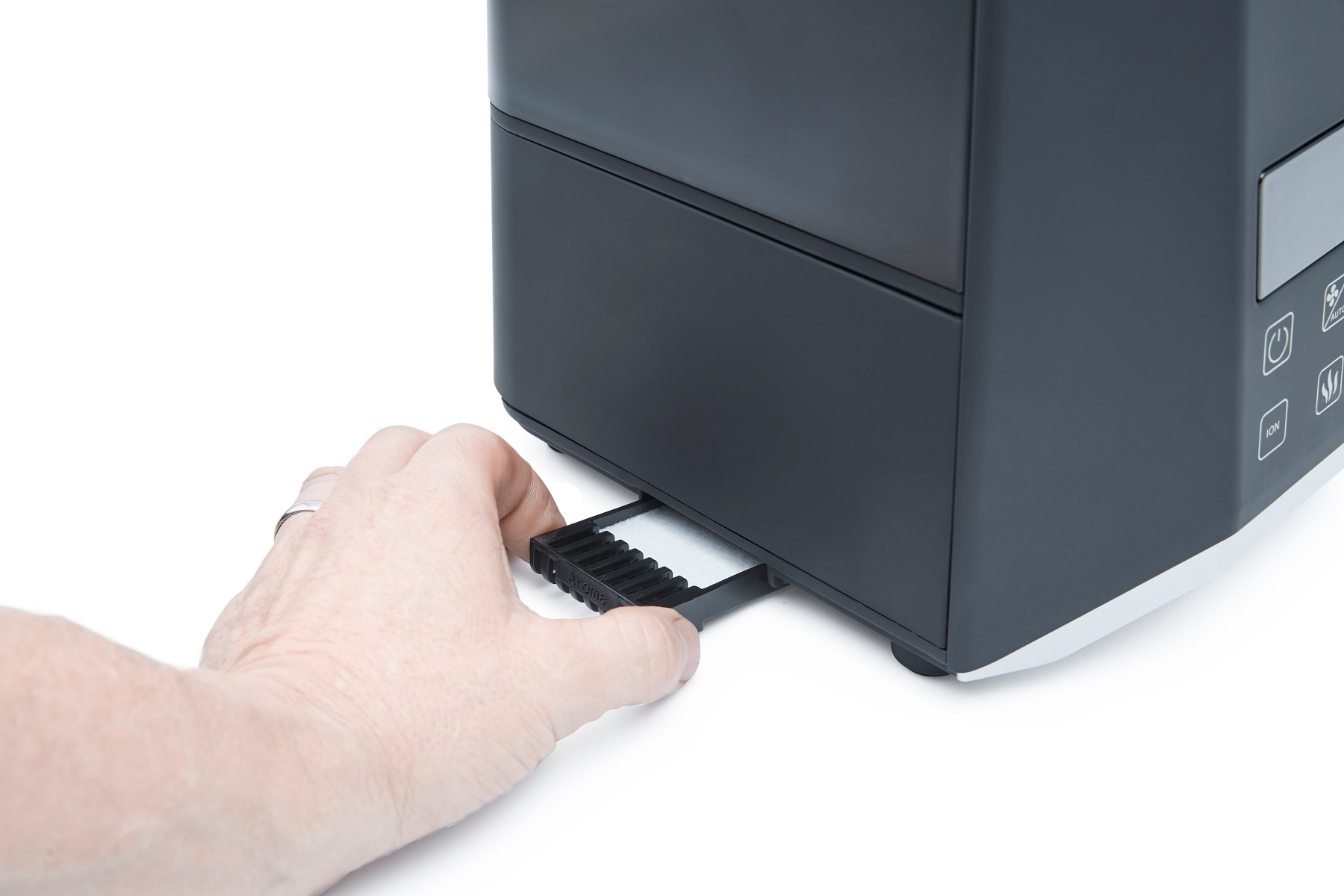 Mano inserisce vassoio nero in dispositivo bianco e nero. Sfondo bianco.