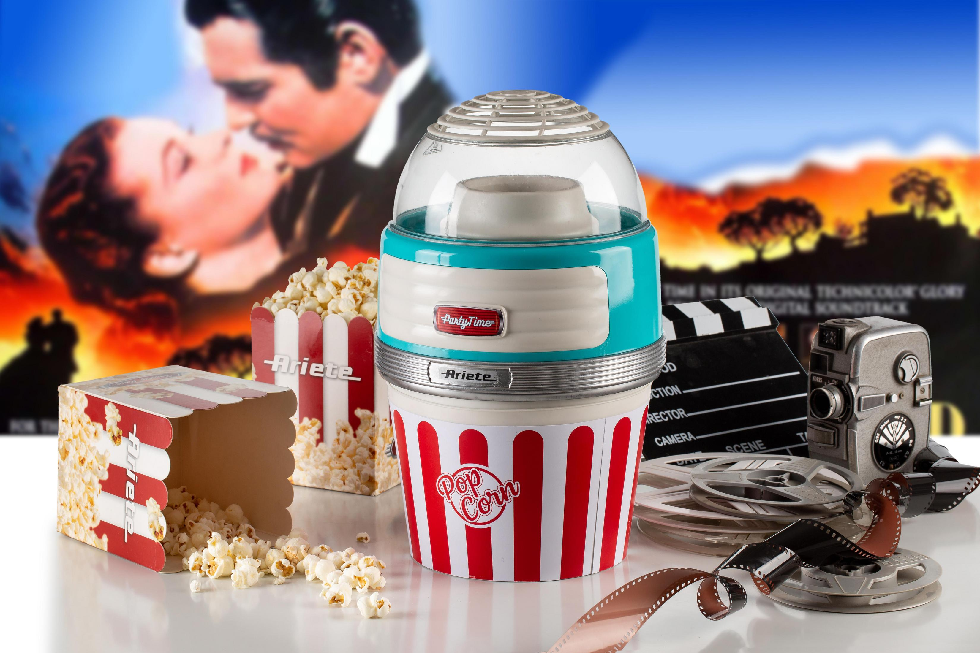 Popcornmaschine mit Popcorn, Popcornboxen, Filmrollen und einem Filmplakat im Hintergrund.
