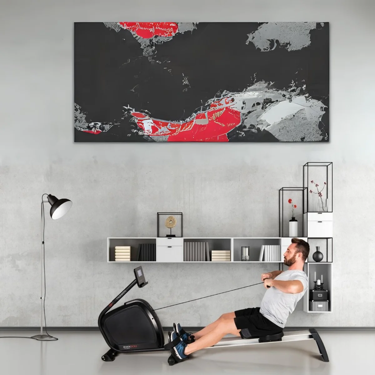 Man rowing on a black rowing machine. Abstract art and shelves are in the background.
