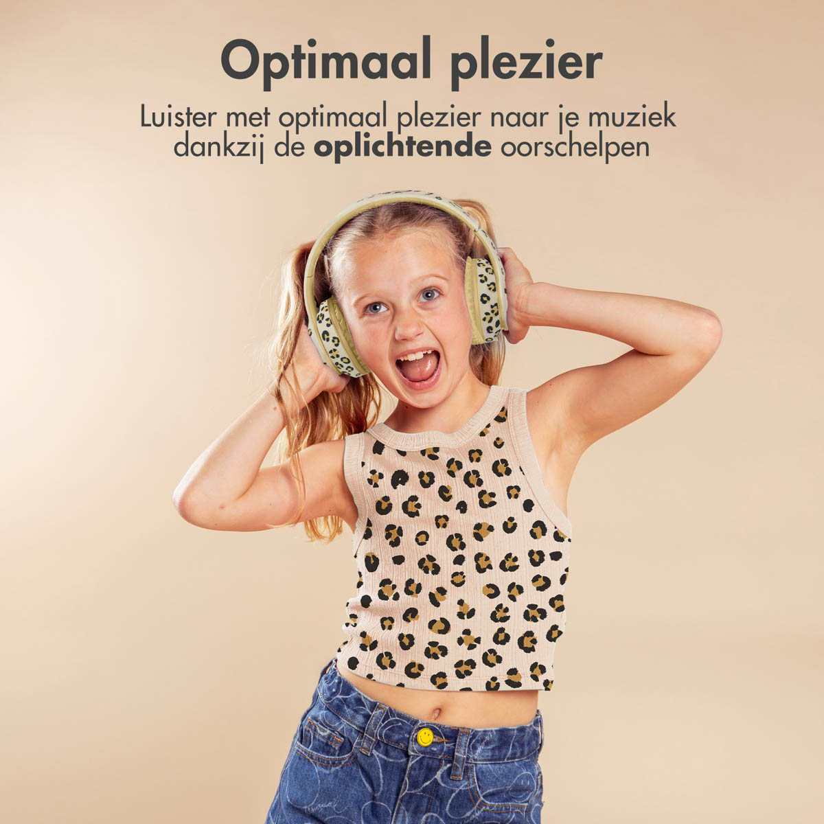Een meisje met een koptelefoon op, lachend en gebarend. De achtergrond is beige.