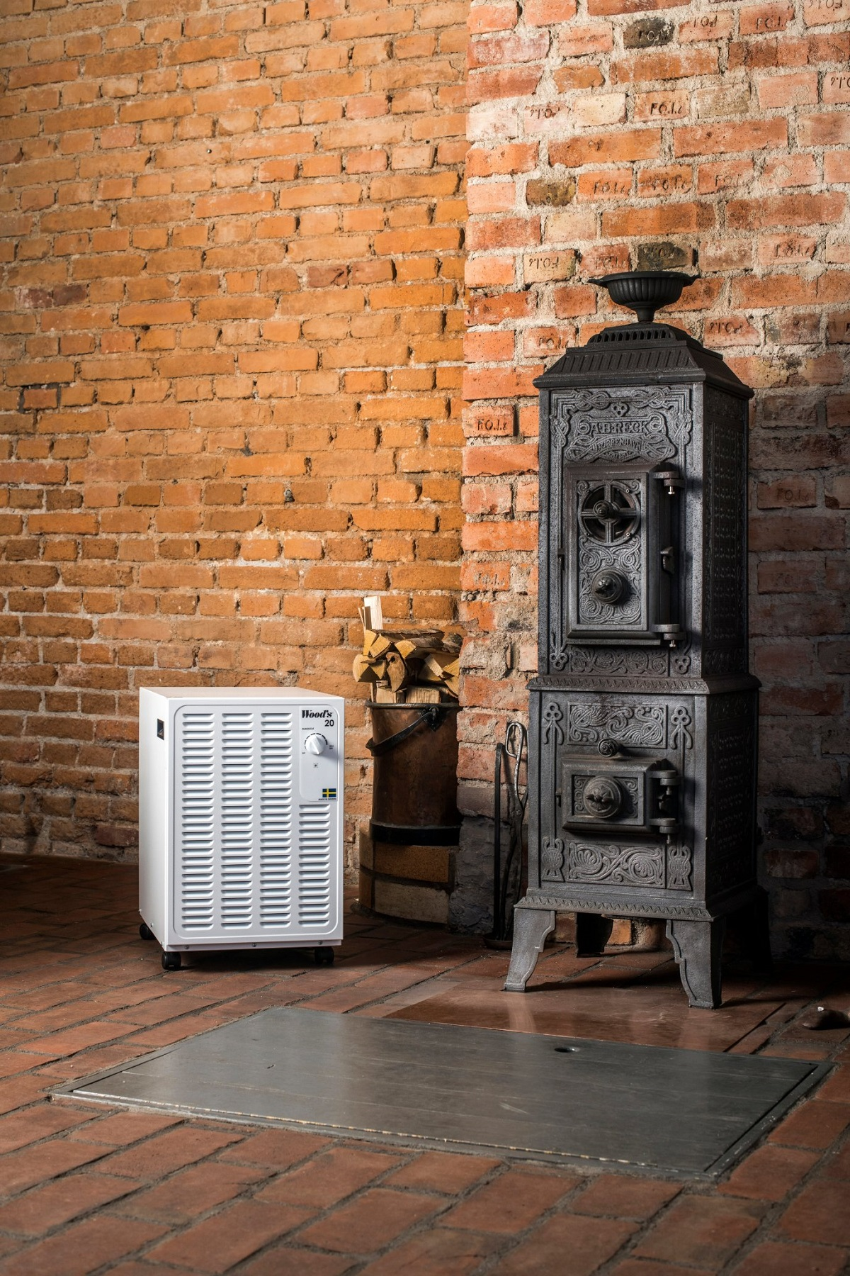 Weißer Ventilator, Backsteinmauer und schwarzer Ofen.