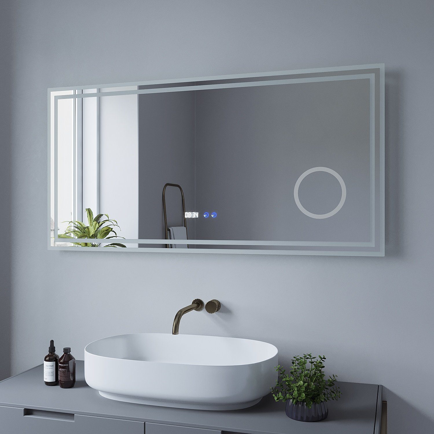 Badezimmer mit großem Spiegel über einem Waschbecken. Der Spiegel hat einen Lichtrand und zeigt die Uhrzeit.