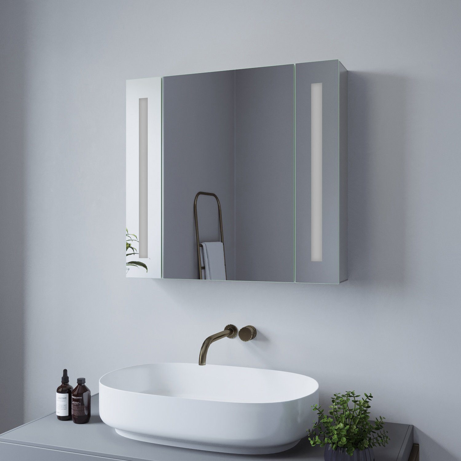 Badezimmerspiegelschrank mit Lichtern, Waschbecken, Wasserhahn und zwei Flaschen.