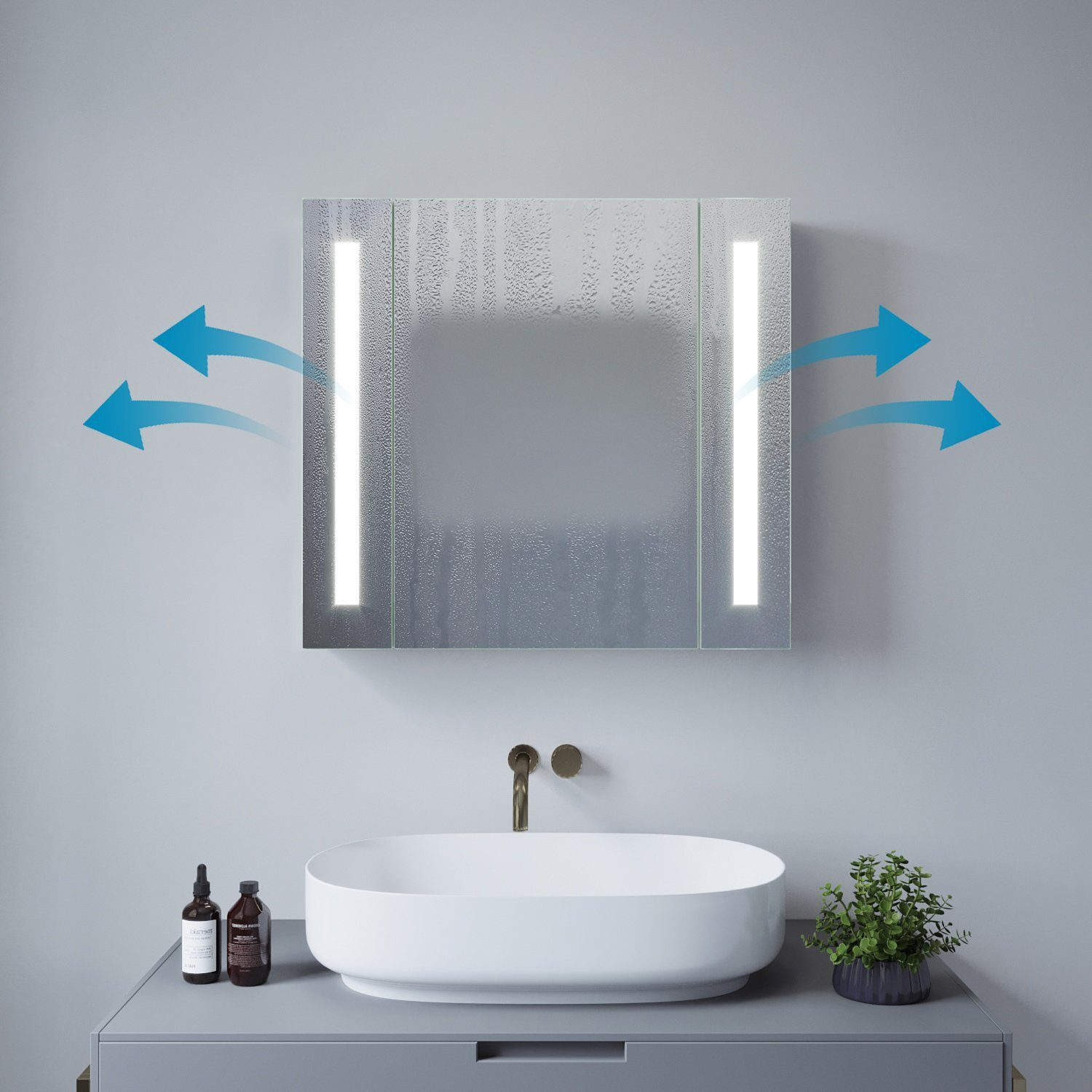 Badspiegel mit LED-Leuchten und blauen Pfeilen, die den Luftstrom anzeigen. Ovales Waschbecken und zwei Flaschen darunter.