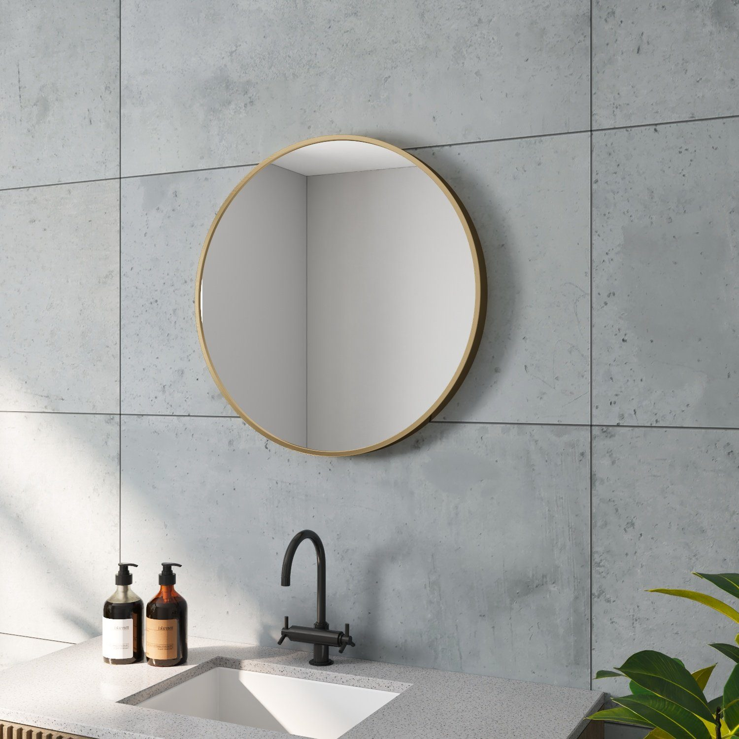 Badezimmer mit rundem Spiegel, Wasserhahn und zwei Flaschen. Graue Fliesenwand und weiße Arbeitsplatte.
