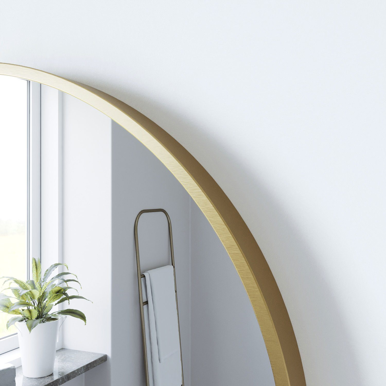 Ein goldener, gewölbter Spiegel mit weißer Wand und Pflanze im Hintergrund.